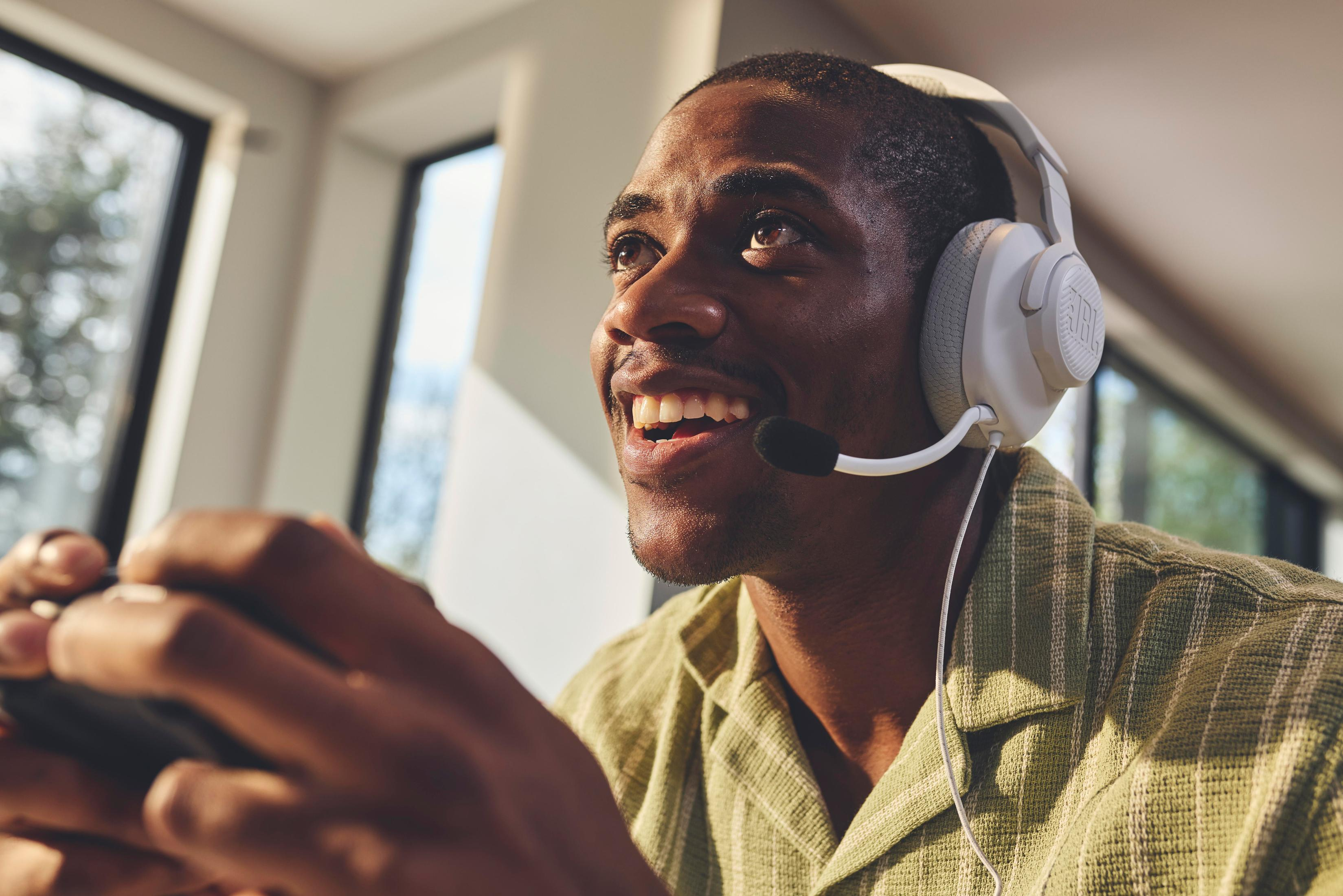 Mężczyzna w słuchawkach, uśmiechnięty, trzymający kontroler do gier.