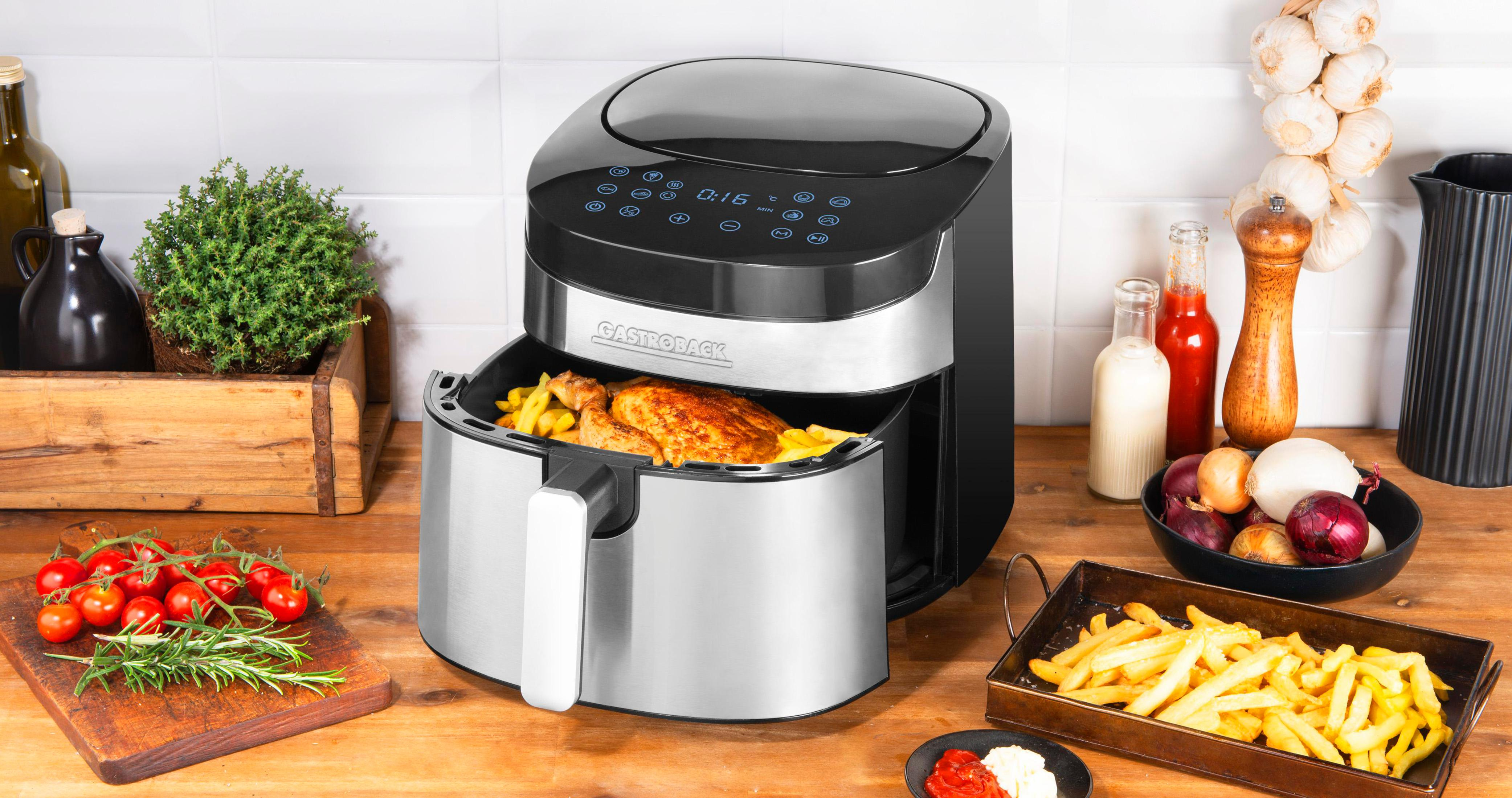 Una friggitrice ad aria con cibo all'interno, circondata da ingredienti e utensili da cucina.