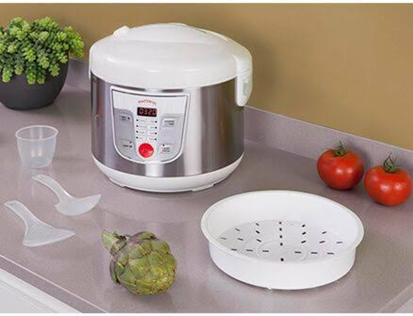 Arrocera, tomates y alcachofa en la encimera. Cesta de vapor y utensilios.