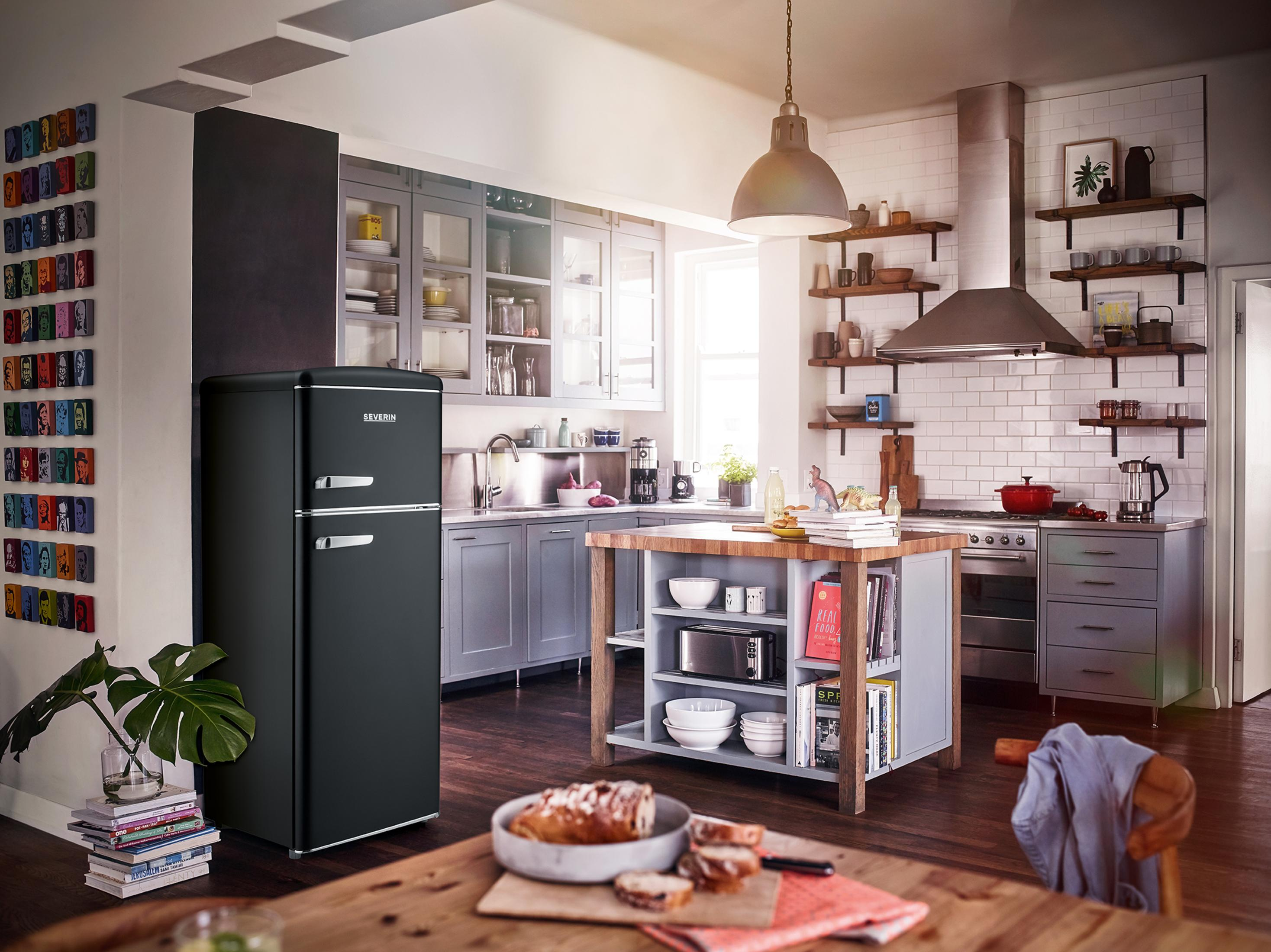 Küche mit einem schwarzen Retro-Kühlschrank. Holztisch und Kücheninsel sind sichtbar.