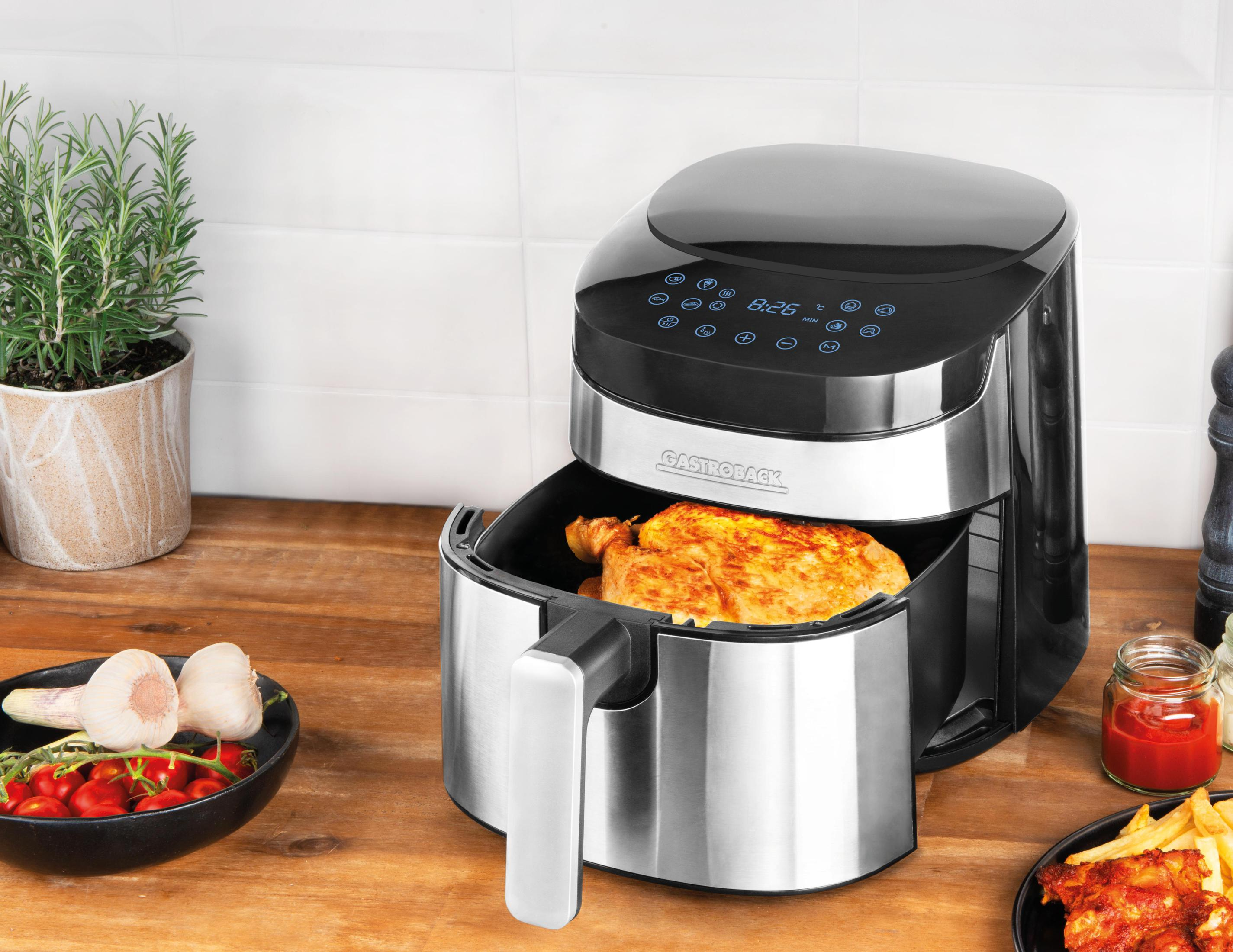 Frytkownica beztłuszczowa z ugotowanym kurczakiem w środku. Warzywa i sos na pierwszym planie.