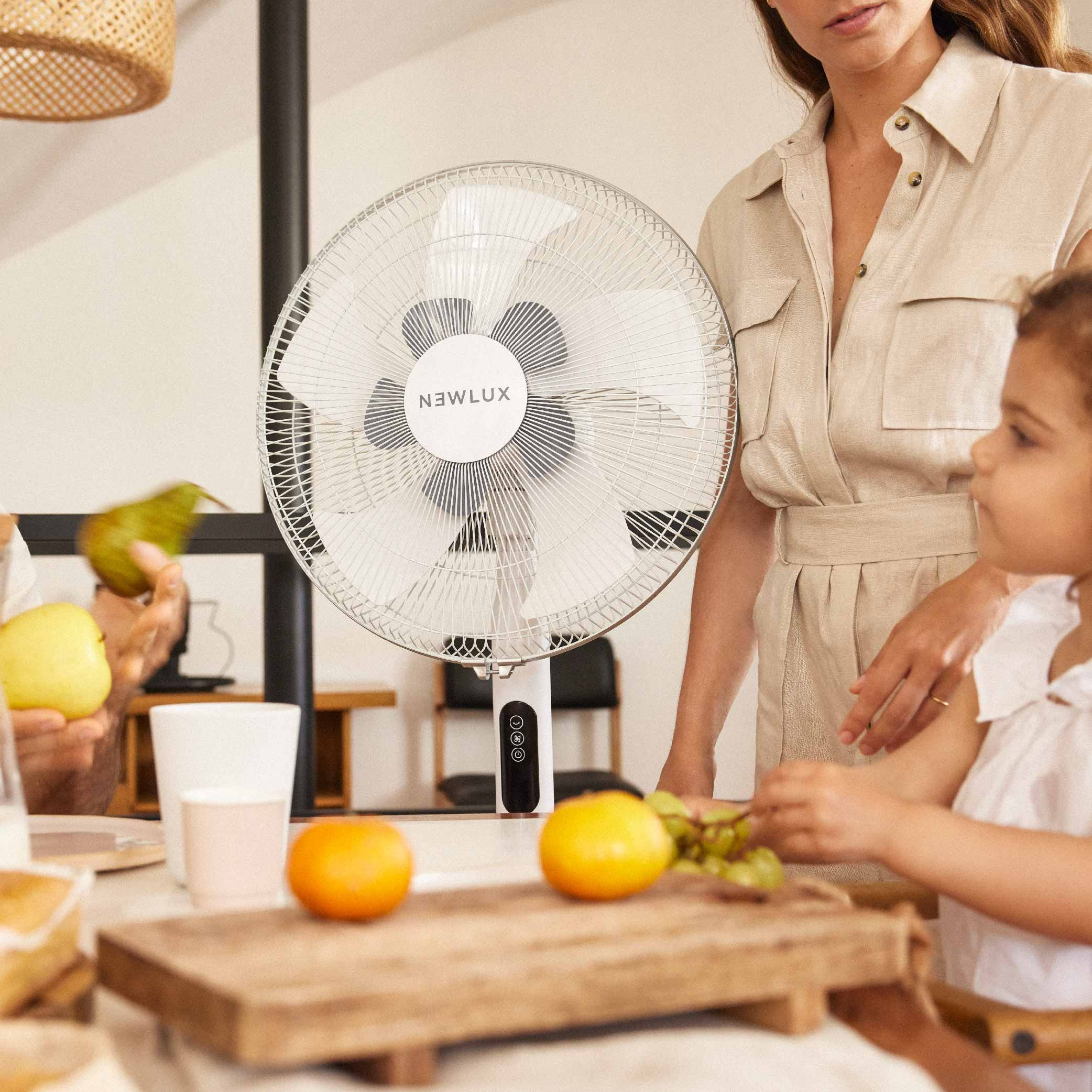 Una mujer y un niño en una mesa con ventilador, comida y bebidas.
