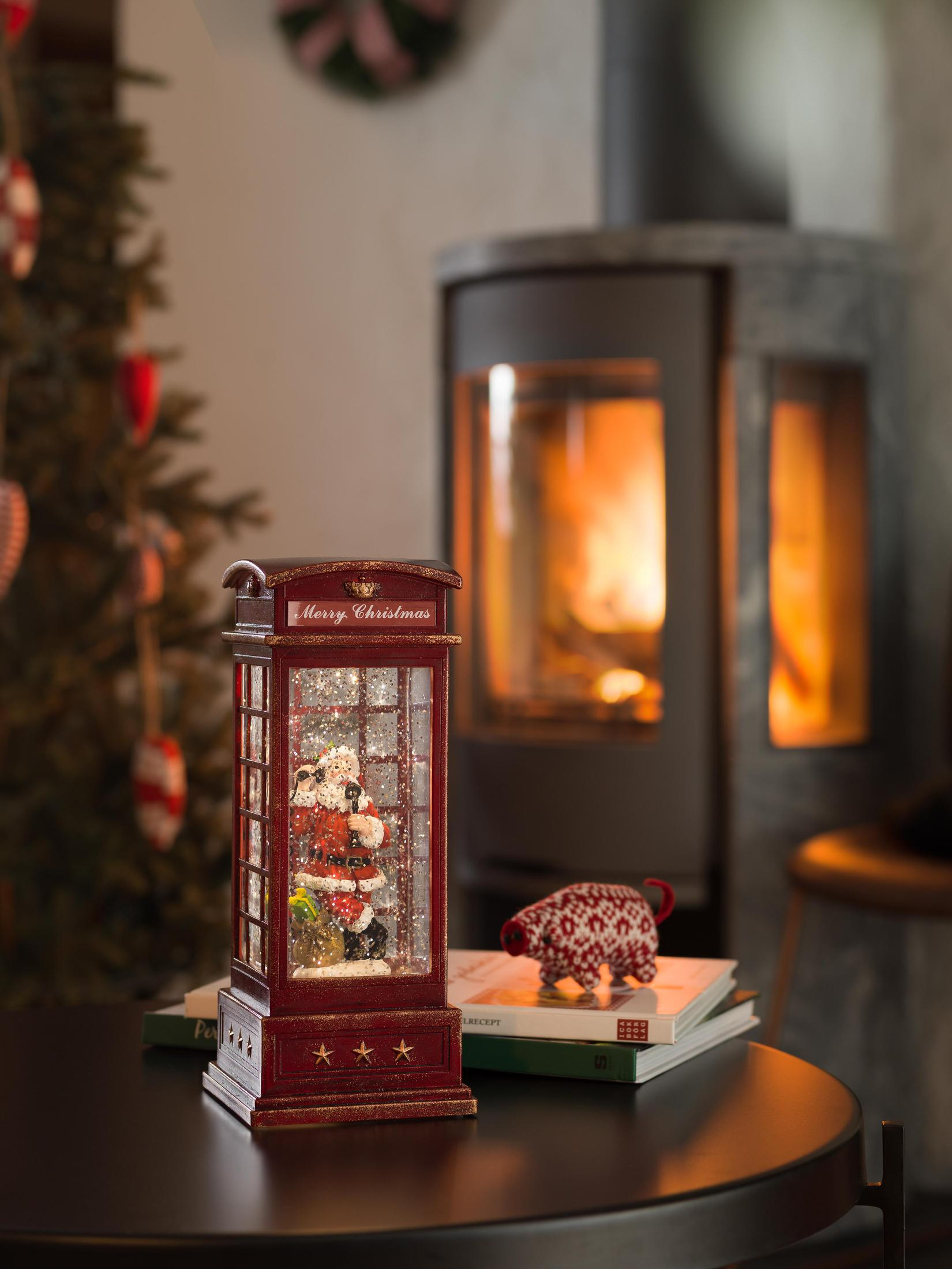 Eine Schneekugel mit Weihnachtsmann, Weihnachtsbaum und Kamin im Hintergrund.
