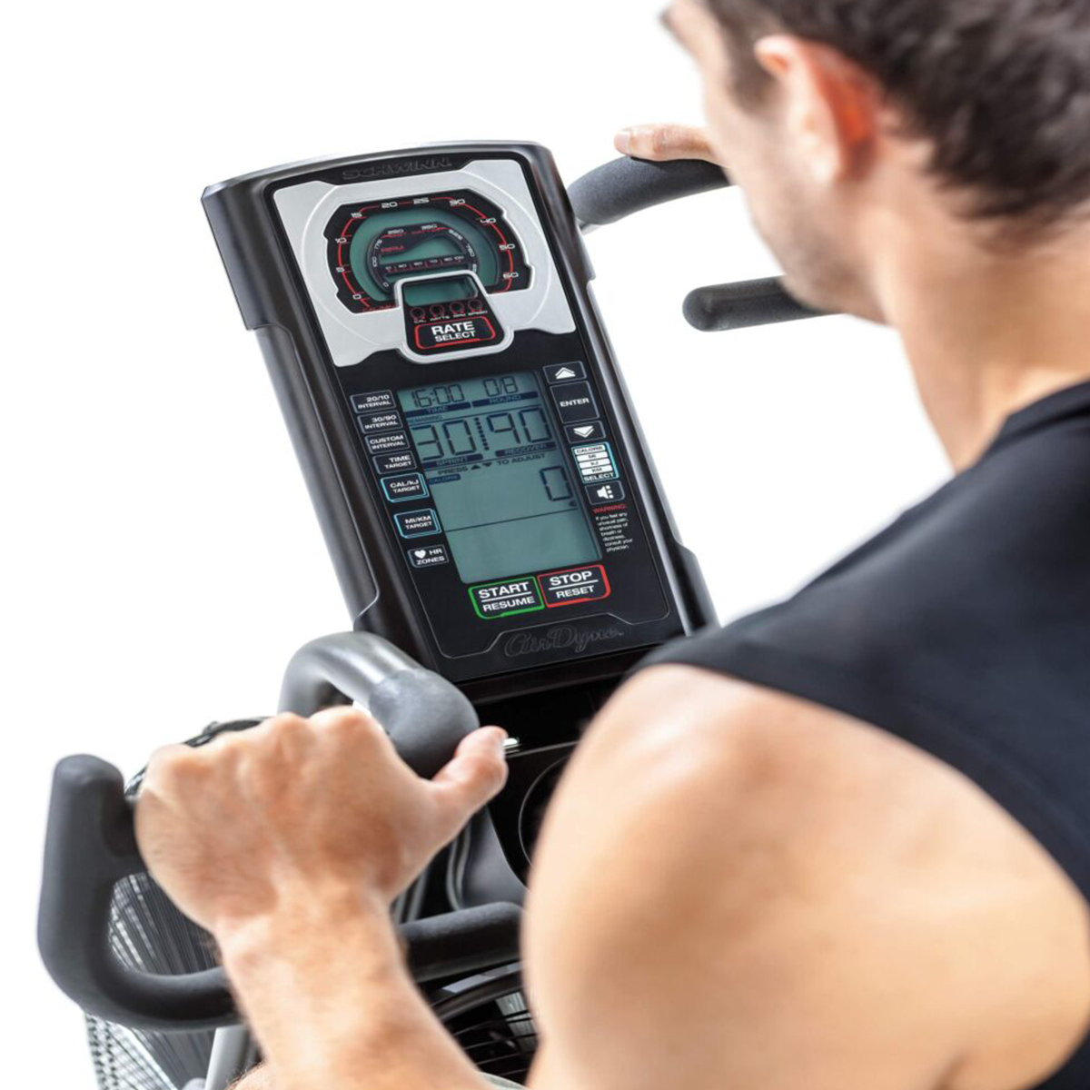 Mężczyzna używa maszyny do ćwiczeń, widok z tyłu, widoczny wyświetlacz cyfrowy.