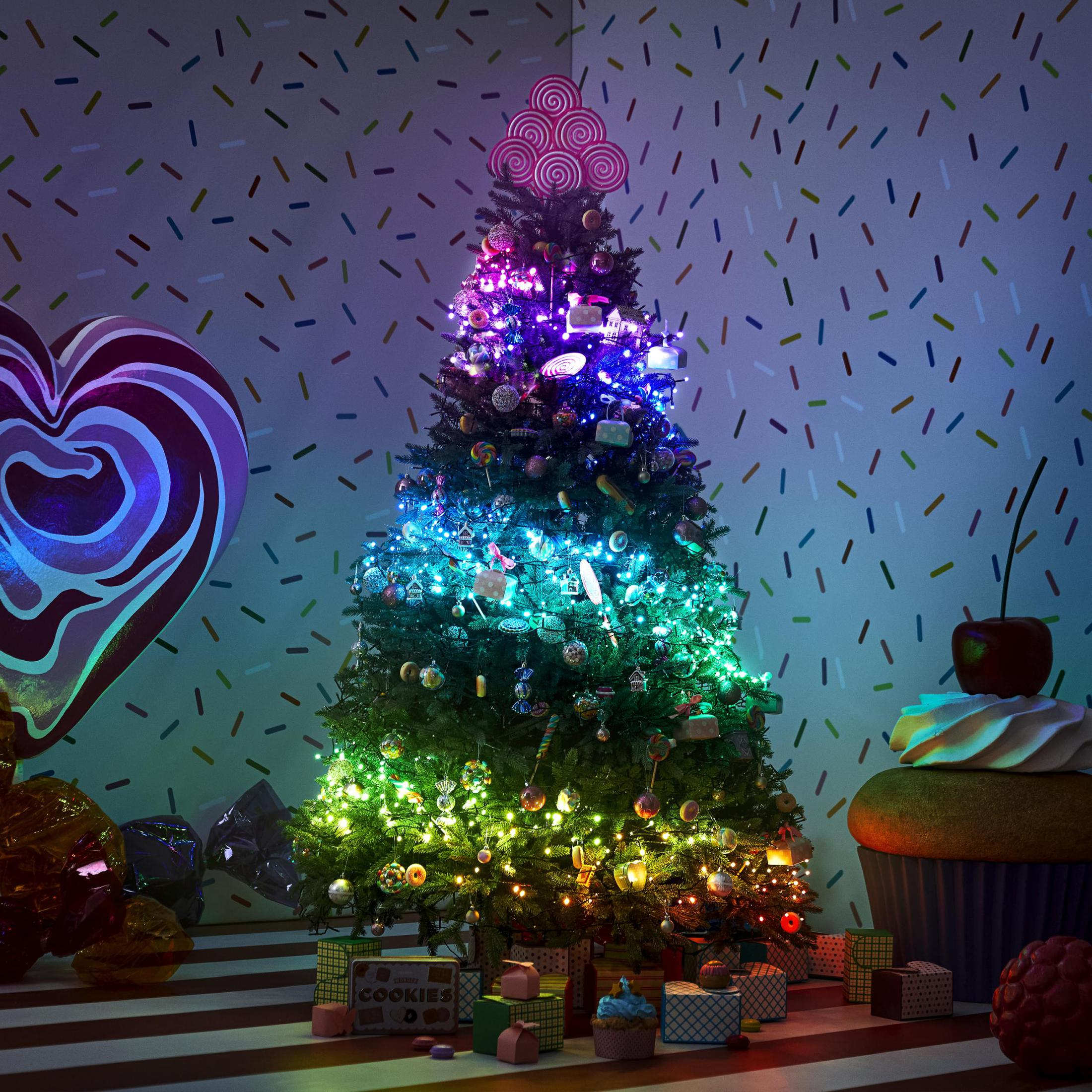 Choinka z kolorowymi światłami, słodyczami, prezentami i dużą dekoracją w kształcie serca.