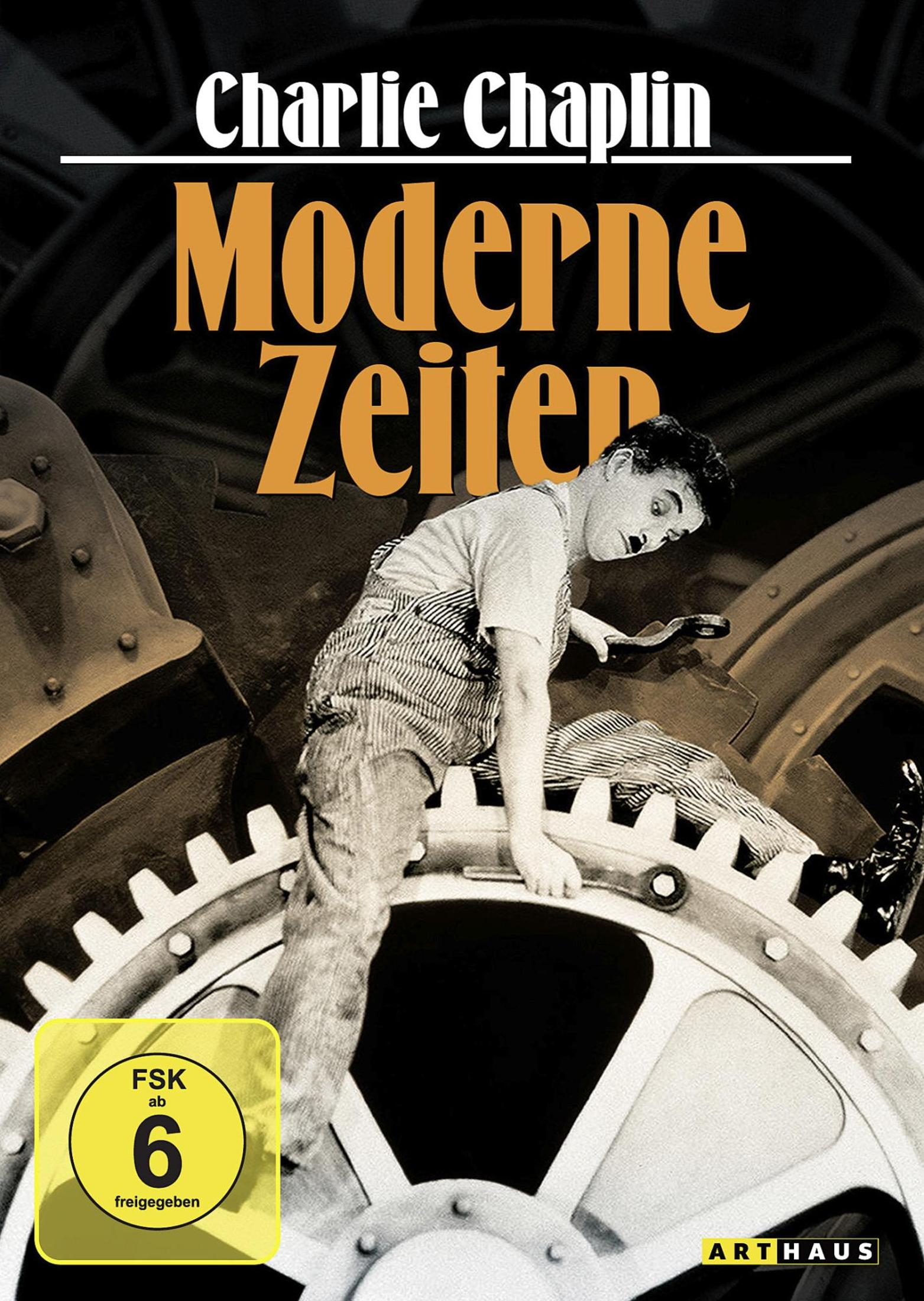 Charlie Chaplin in Lumpen klettert auf einem großen Zahnrad mit dem Filmtitel 'Moderne Zeiten'.