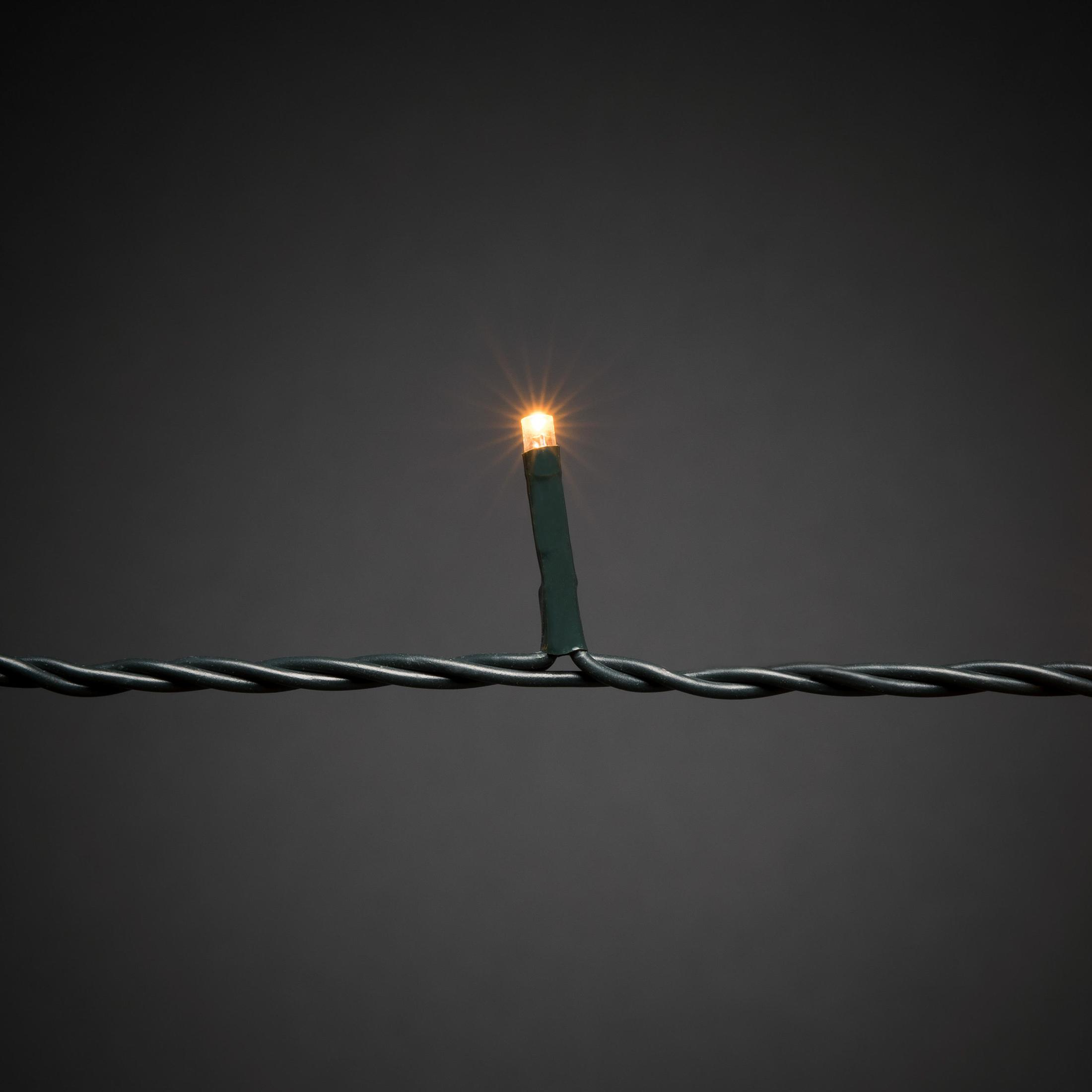 Nahaufnahme einer einzelnen LED-Leuchte an einem grünen Draht. Das Licht ist hell und gelb.