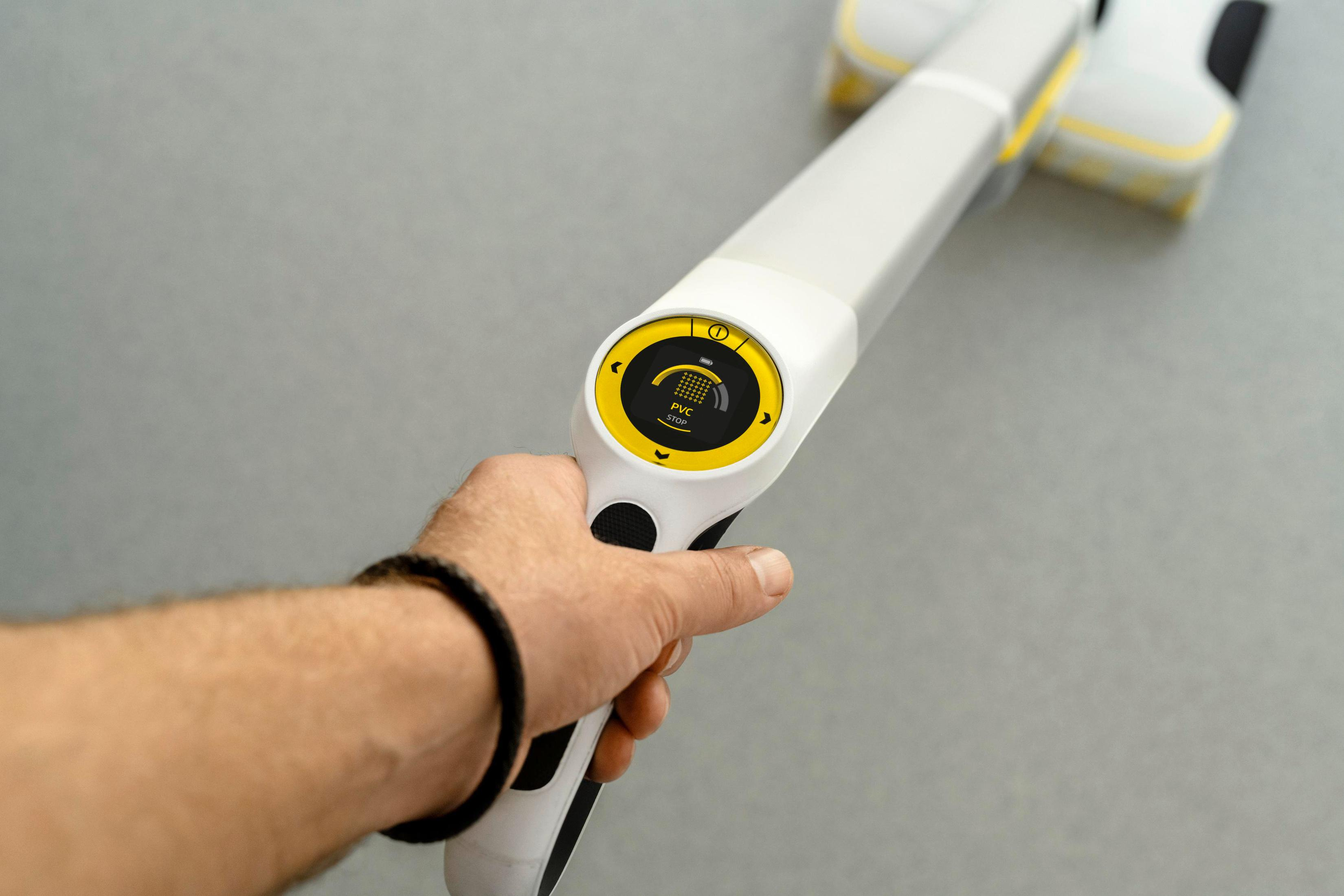 Una mano che tiene un dispositivo di pulizia bianco con display e pulsanti gialli.
