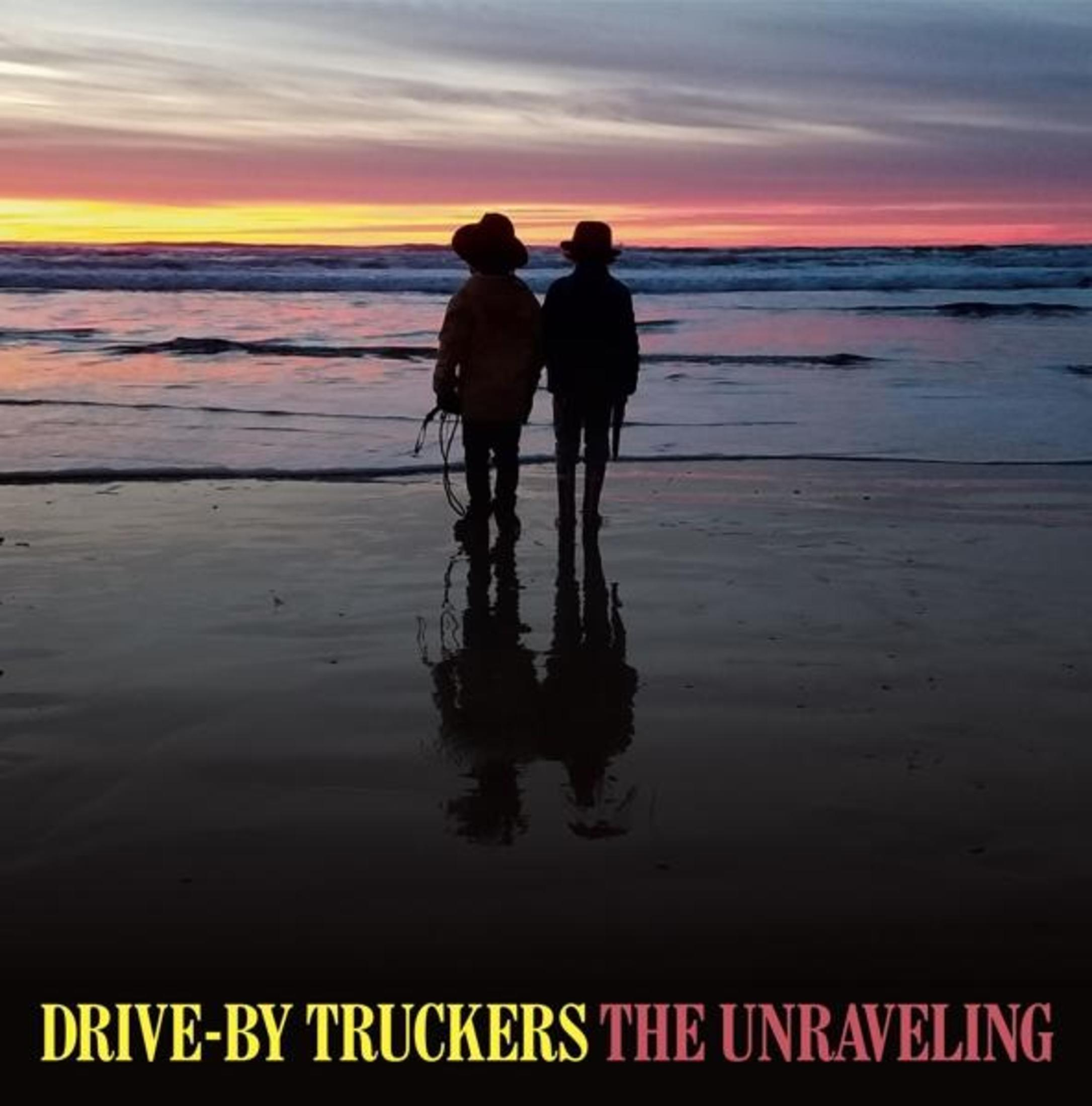 Deux personnages se tiennent sur une plage, face à l'océan au coucher du soleil. Le texte de l'album est en bas.