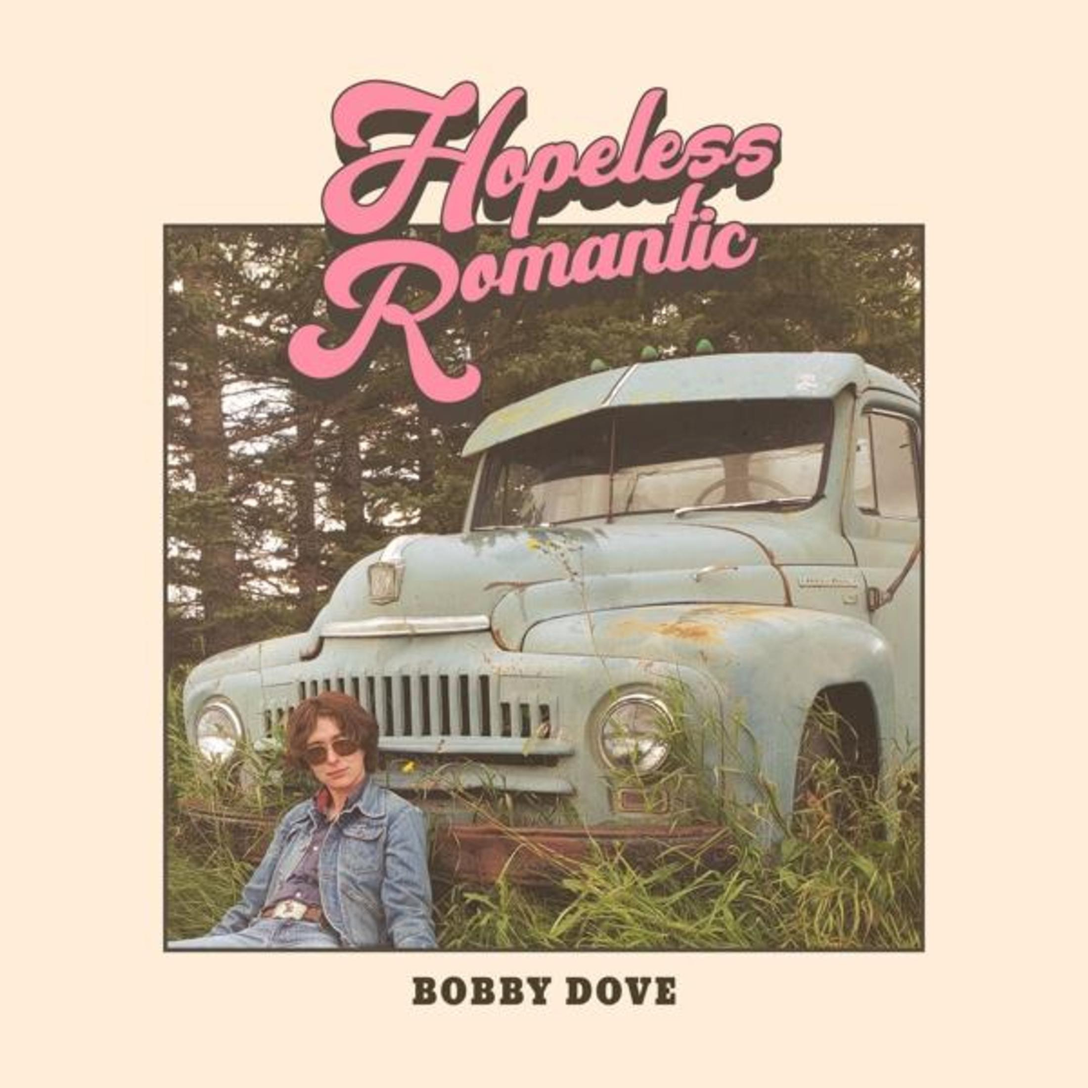 Pochette d'album avec une femme assise devant un vieux camion bleu, avec un titre rose qui dit "Hopeless Romantic".