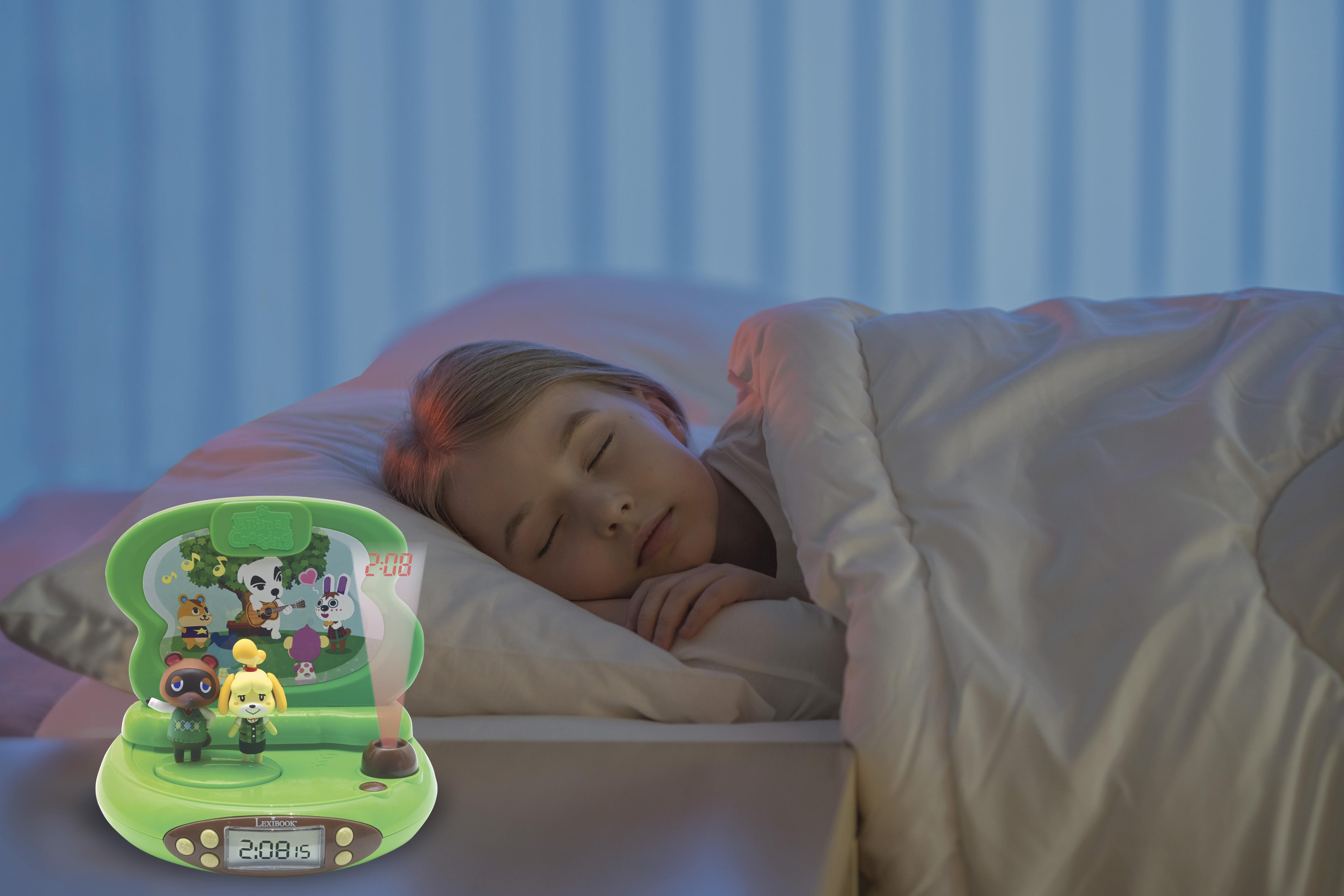 Un bambino dorme accanto a una sveglia di Animal Crossing con base verde.