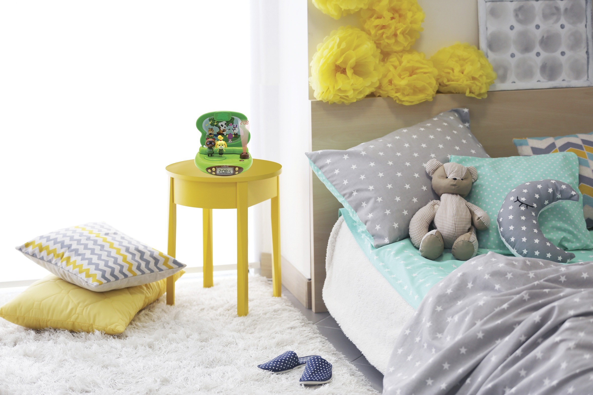 Tavolo giallo con giocattolo verde, cuscini e letto con stelle.