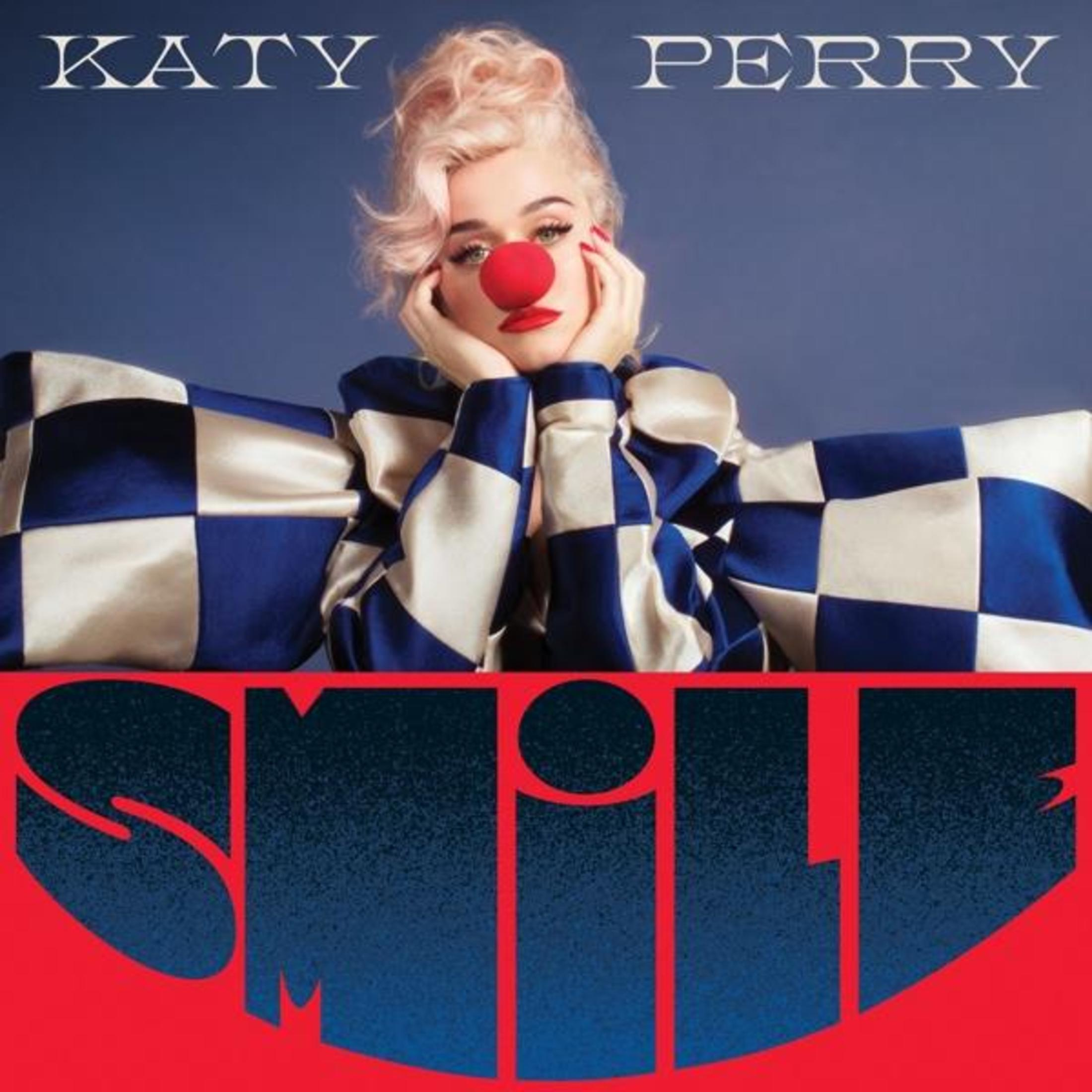 Katy Perry Albumcover. Gesicht mit roter Nase, blau kariertes Outfit und das Wort 'SMILE' auf dem Cover.