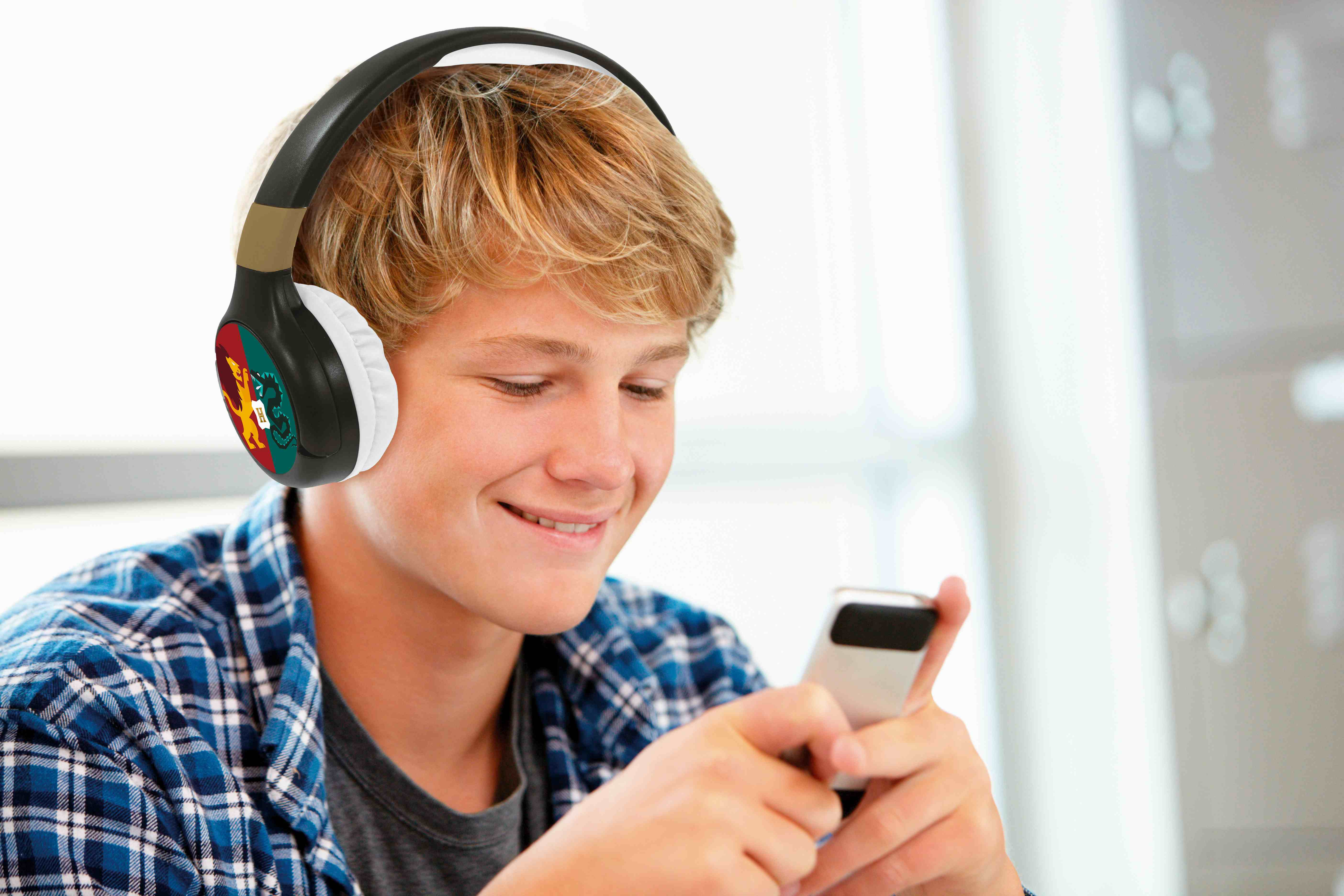 Adolescente con auriculares, sonriendo, usando un smartphone. Fondo borroso.