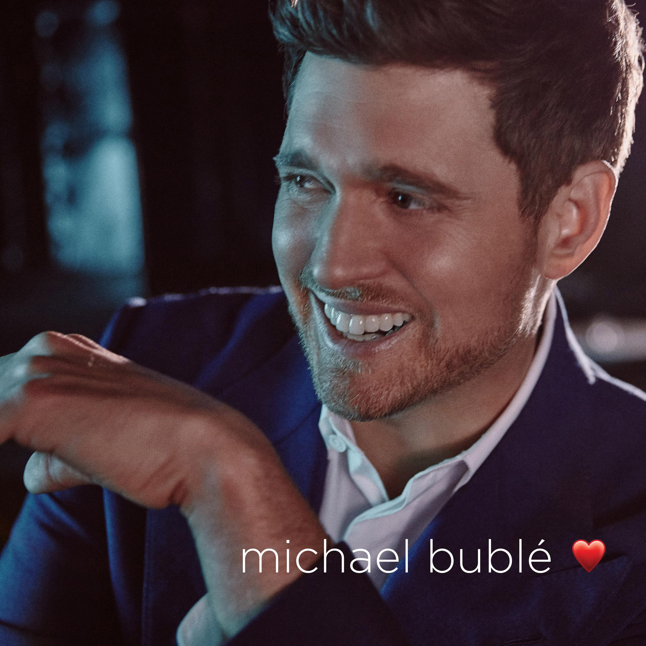 Michael Bublé sorridente, in abito blu. Scritta "michael bublé" e un cuore rosso.