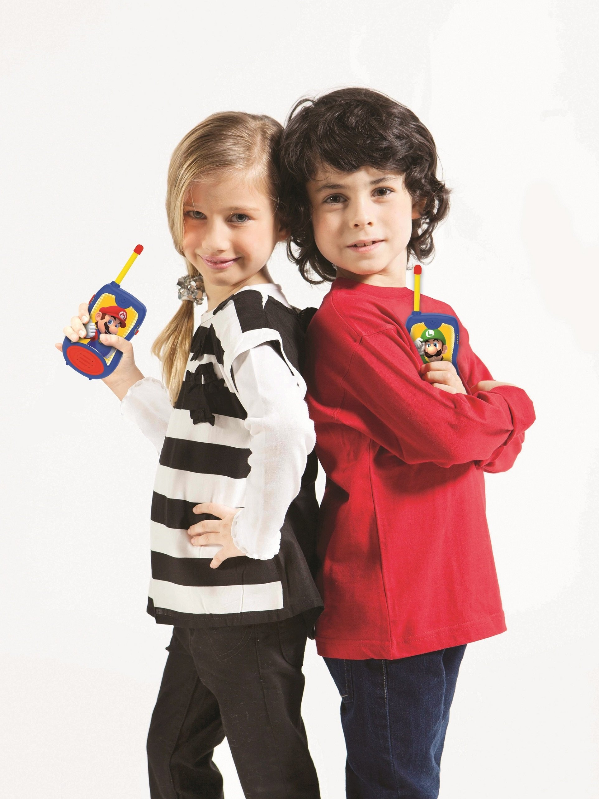 Dos niños, espalda con espalda, sosteniendo walkie-talkies de Mario y Luigi. Niña a rayas, niño en rojo.