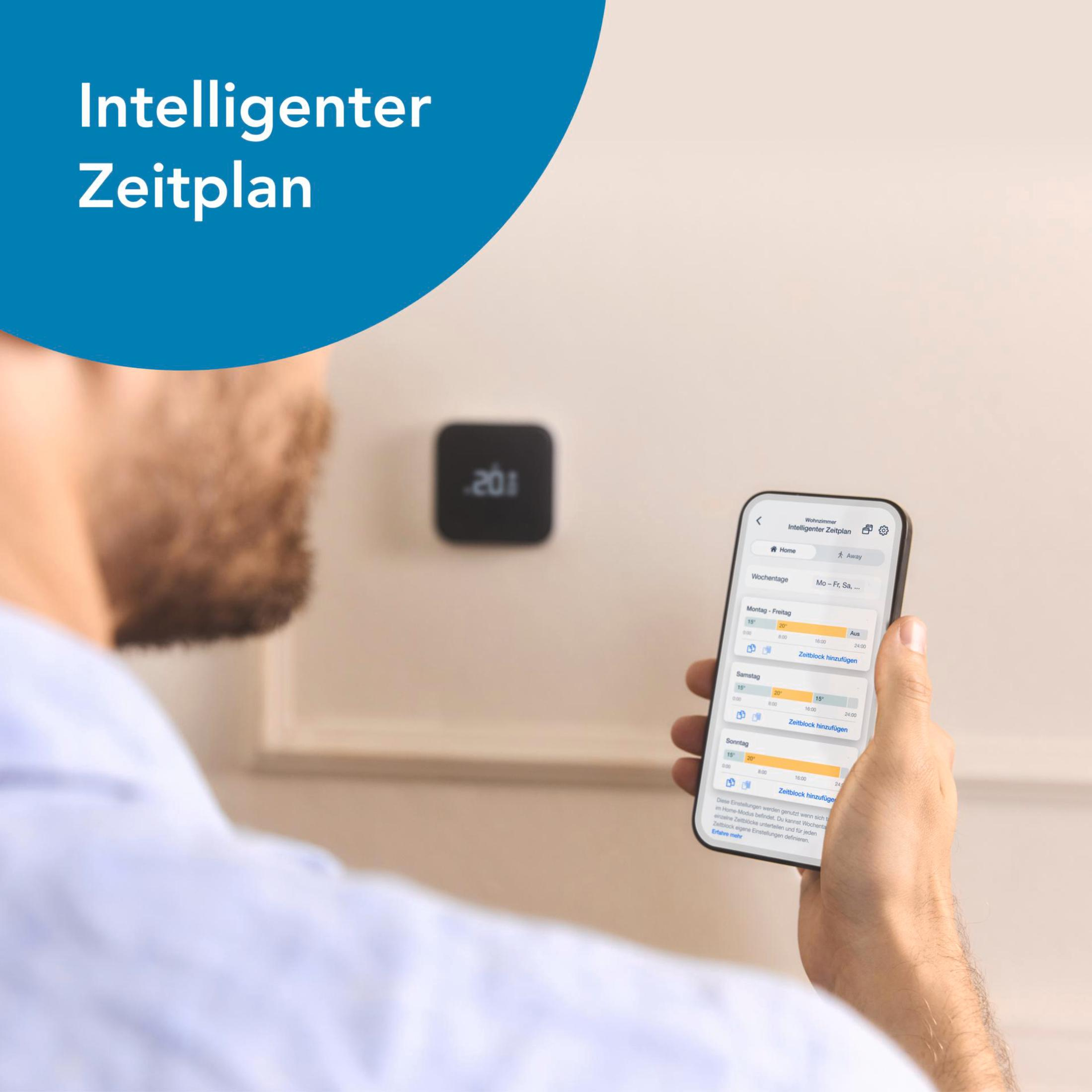 Man bekijkt smart home-bediening op telefoon, met slimme thermostaat aan de muur.