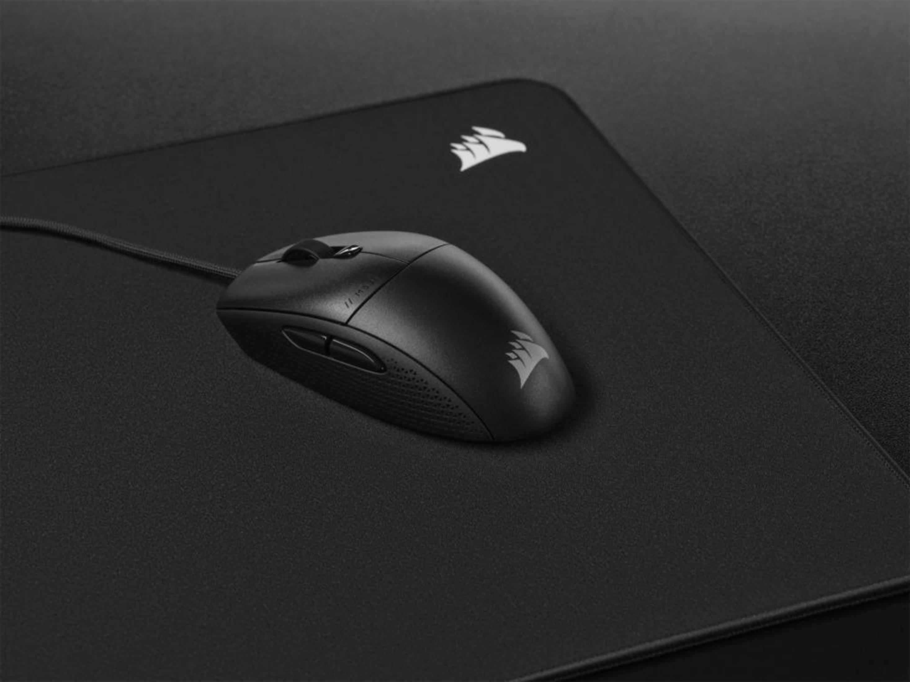 Czarna mysz na czarnej podkładce. Mysz ma logo Corsair. Tło jest czarne.