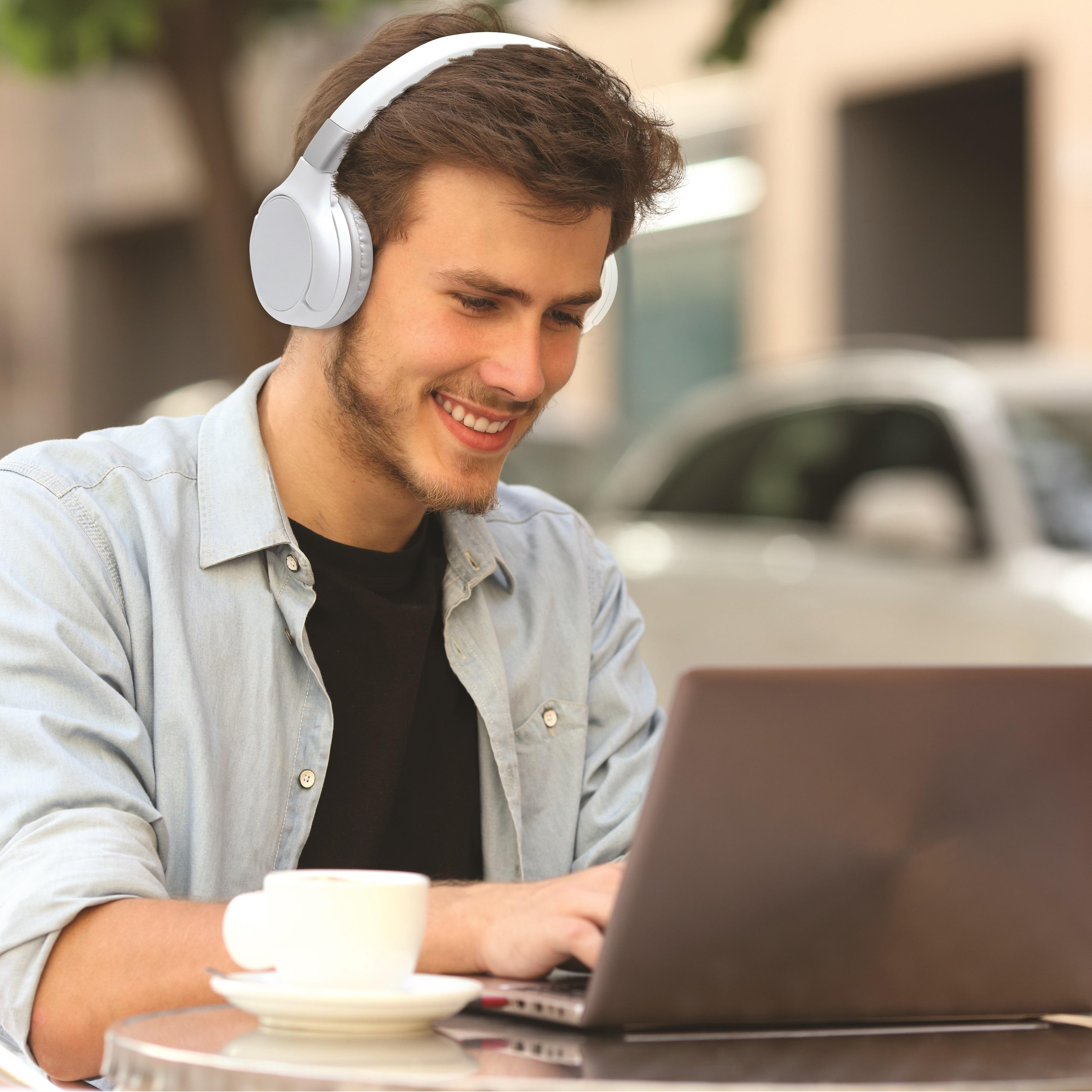 Ein Mann mit weißen Kopfhörern, der einen Laptop benutzt, sitzt in einem Café.