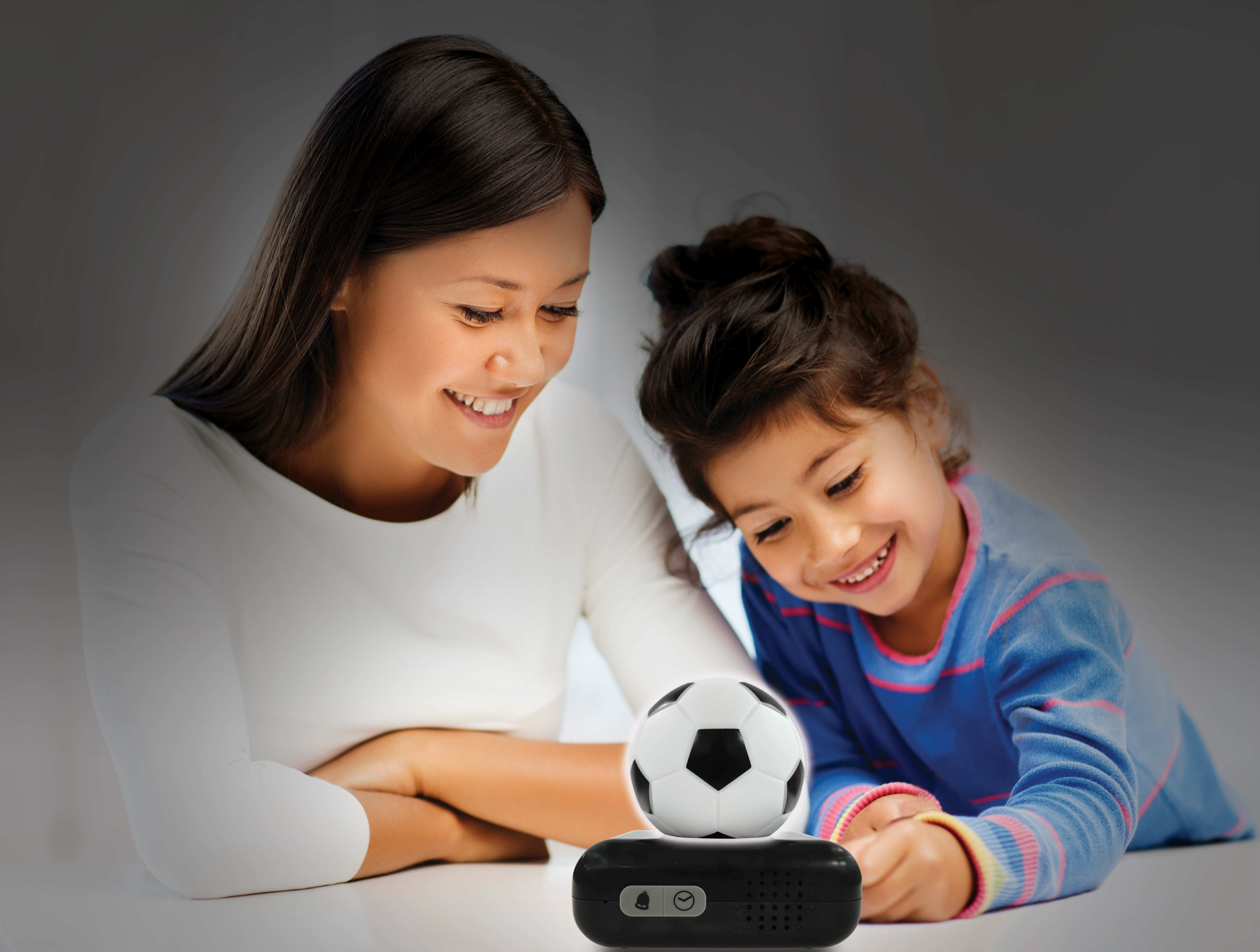 Mujer y niño mirando un balón de fútbol sobre una base negra. Están sonriendo.