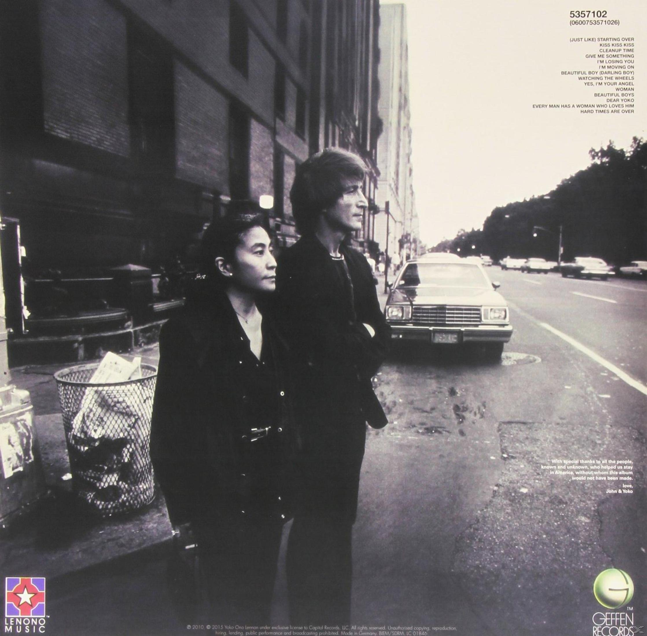John Lennon e Yoko Ono che camminano per strada, foto in bianco e nero.