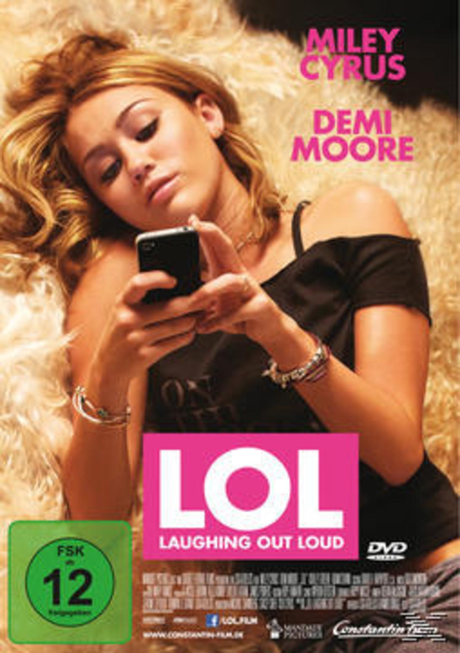 Miley Cyrus hält ein Telefon. Rosa „LOL“-Filmplakat vor ihr. Der Hintergrund ist eine flauschige Decke.