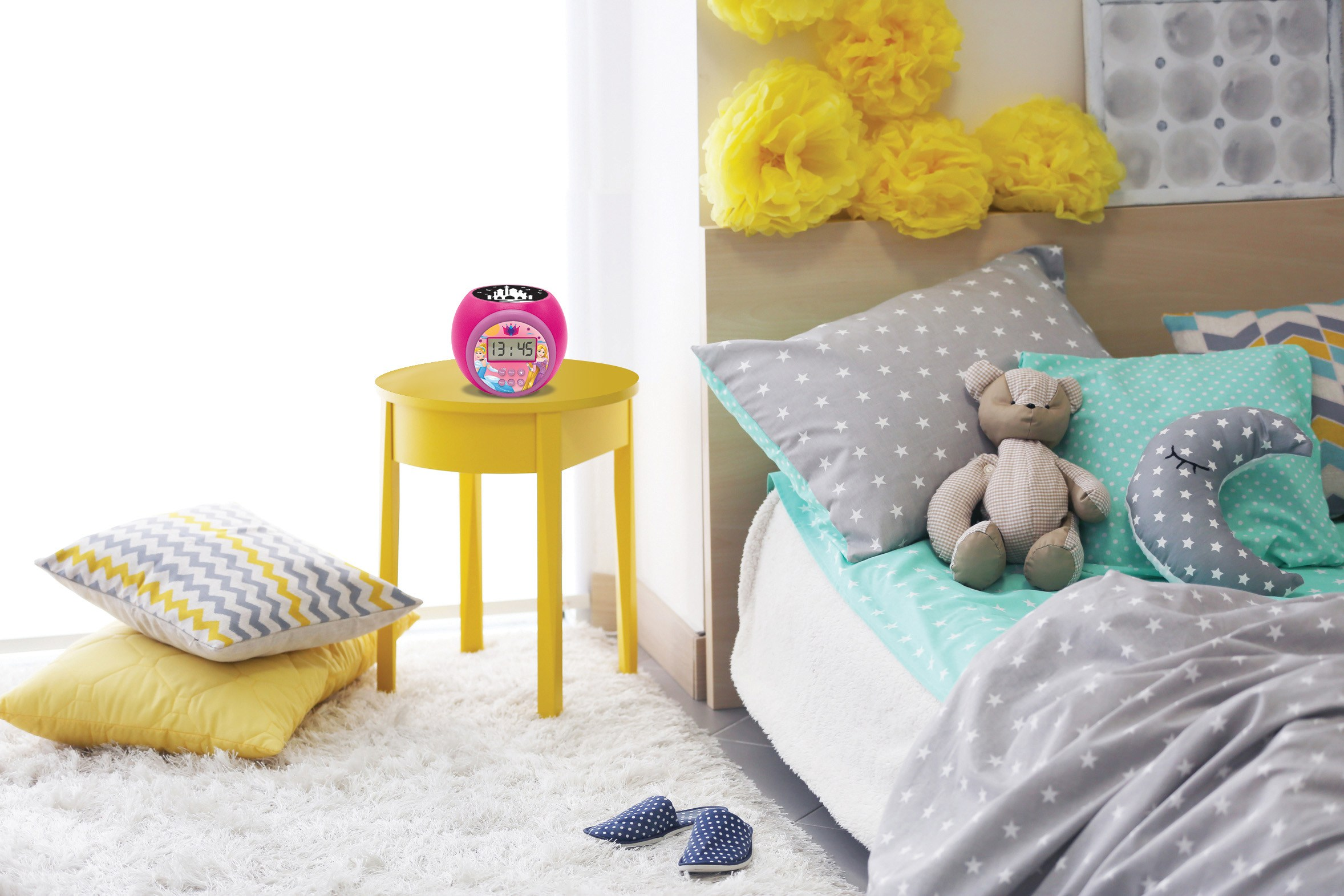 Una sveglia rosa e giocattoli su un tavolo giallo in una camera da letto.