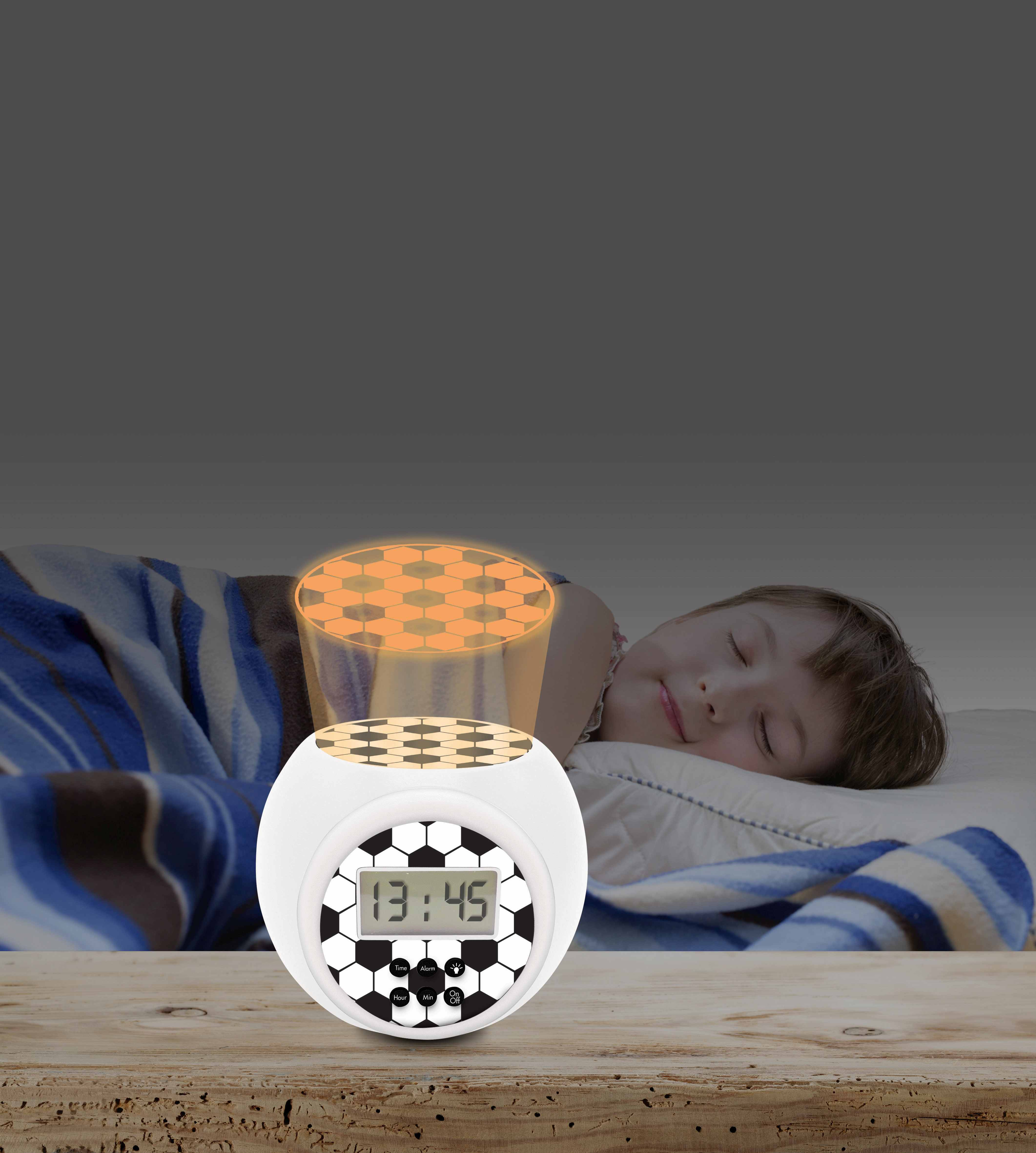Un niño duerme cerca de un despertador con temática de balón de fútbol que muestra 13:45. Una luz naranja brilla arriba.