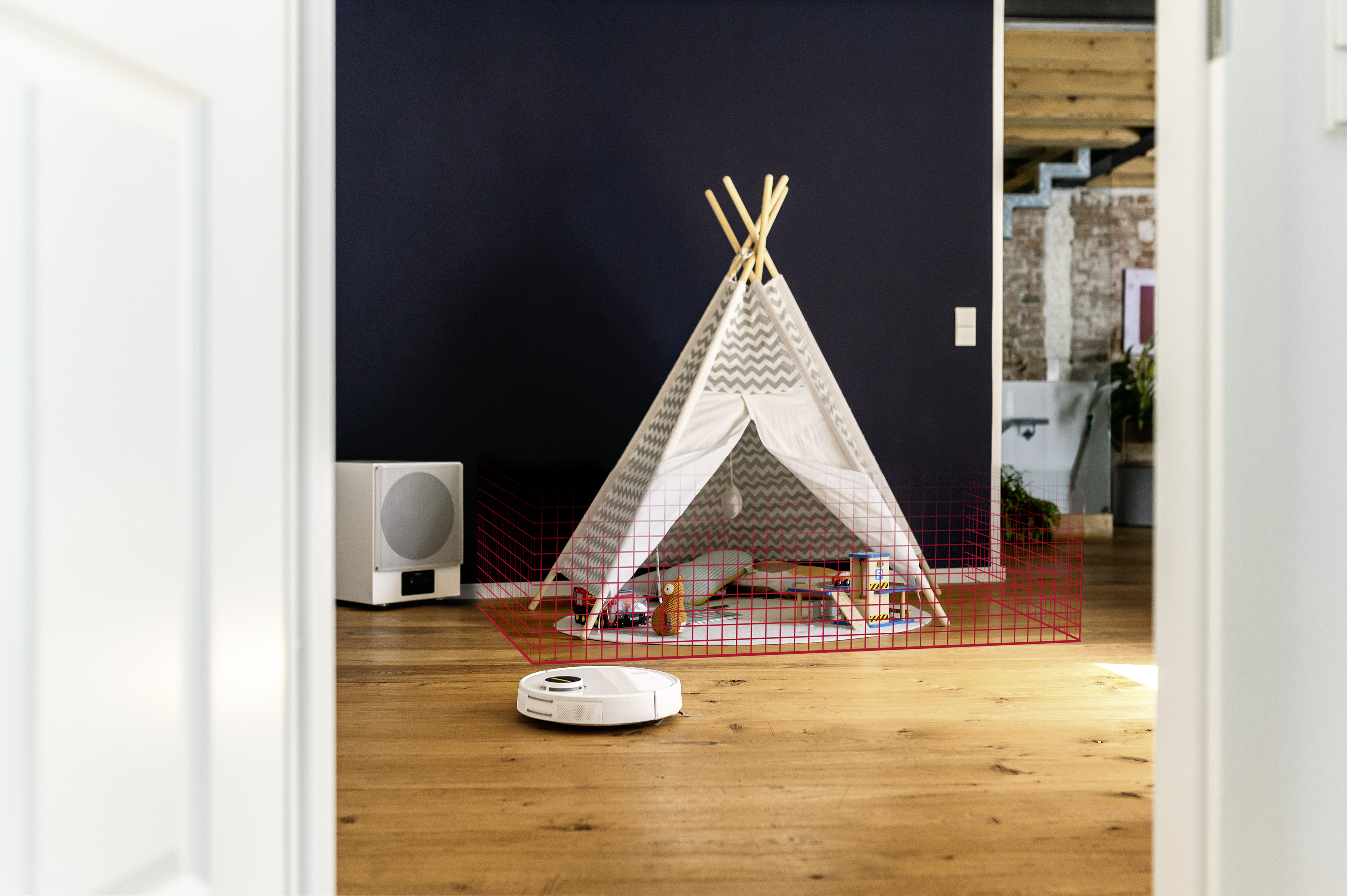 Chambre avec tipi, jouets et un aspirateur robot.