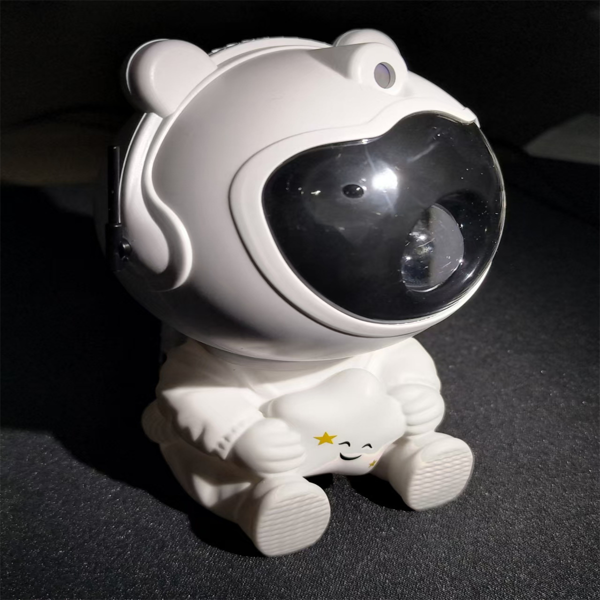 Weiße Astronautenlampe, die eine Wolke hält. Der Astronaut hat ein schwarzes Visier. Die Wolke hat ein lächelndes Gesicht.
