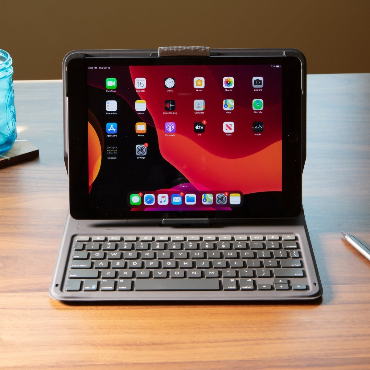 iPad con funda de teclado. Muestra la pantalla de inicio con iconos de aplicaciones.