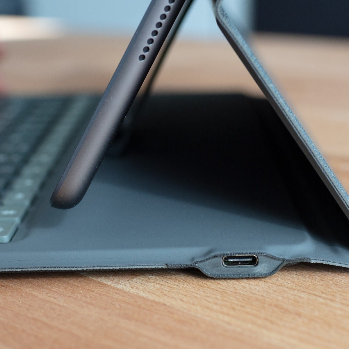 Primer plano de una tableta y una funda con teclado. La tableta tiene un puerto de carga.