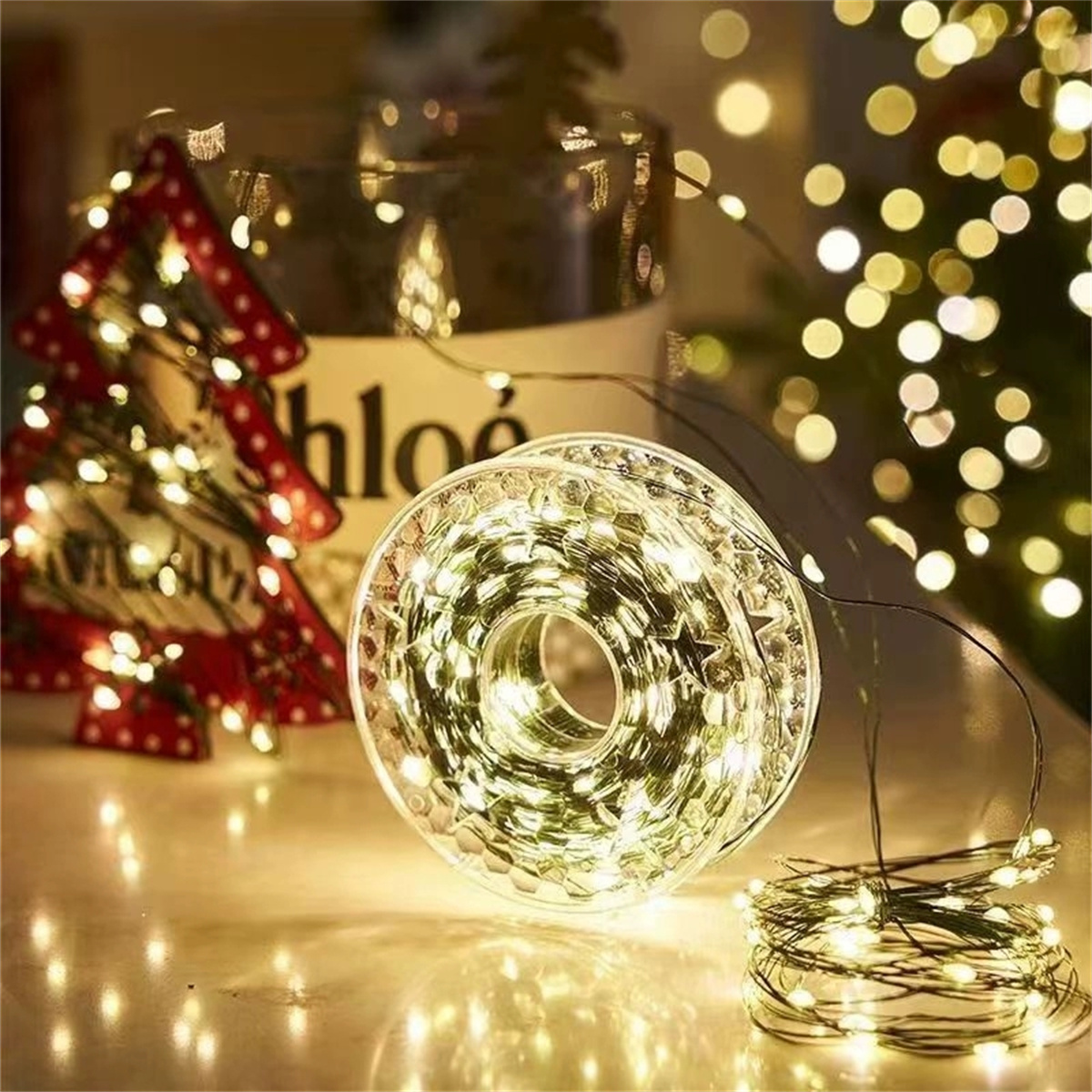 Eine Lichterkette auf einem Tisch, mit Weihnachtsdekorationen im Hintergrund.