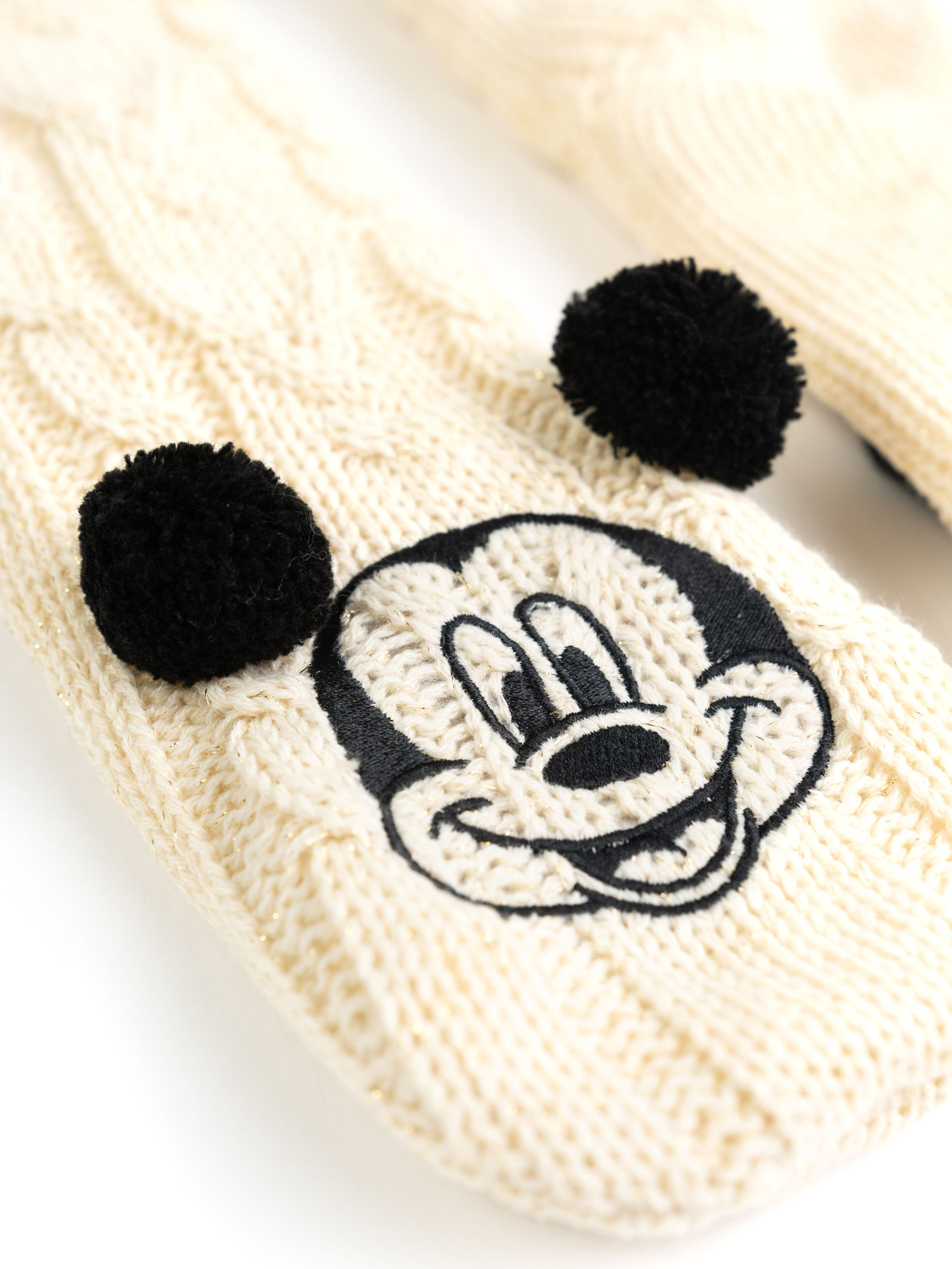Nahaufnahme von cremefarbenen Zopfstricksocken mit Mickey Mouse Gesicht.