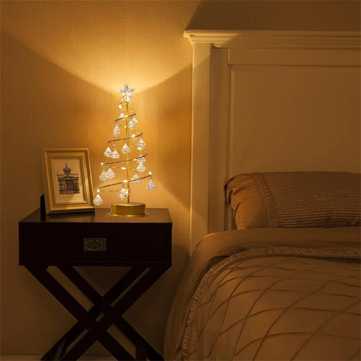 Beleuchteter Weihnachtsbaum mit Ornamenten und Stern. Auf einem Nachttisch neben einem Bett platziert. Warmes Licht.