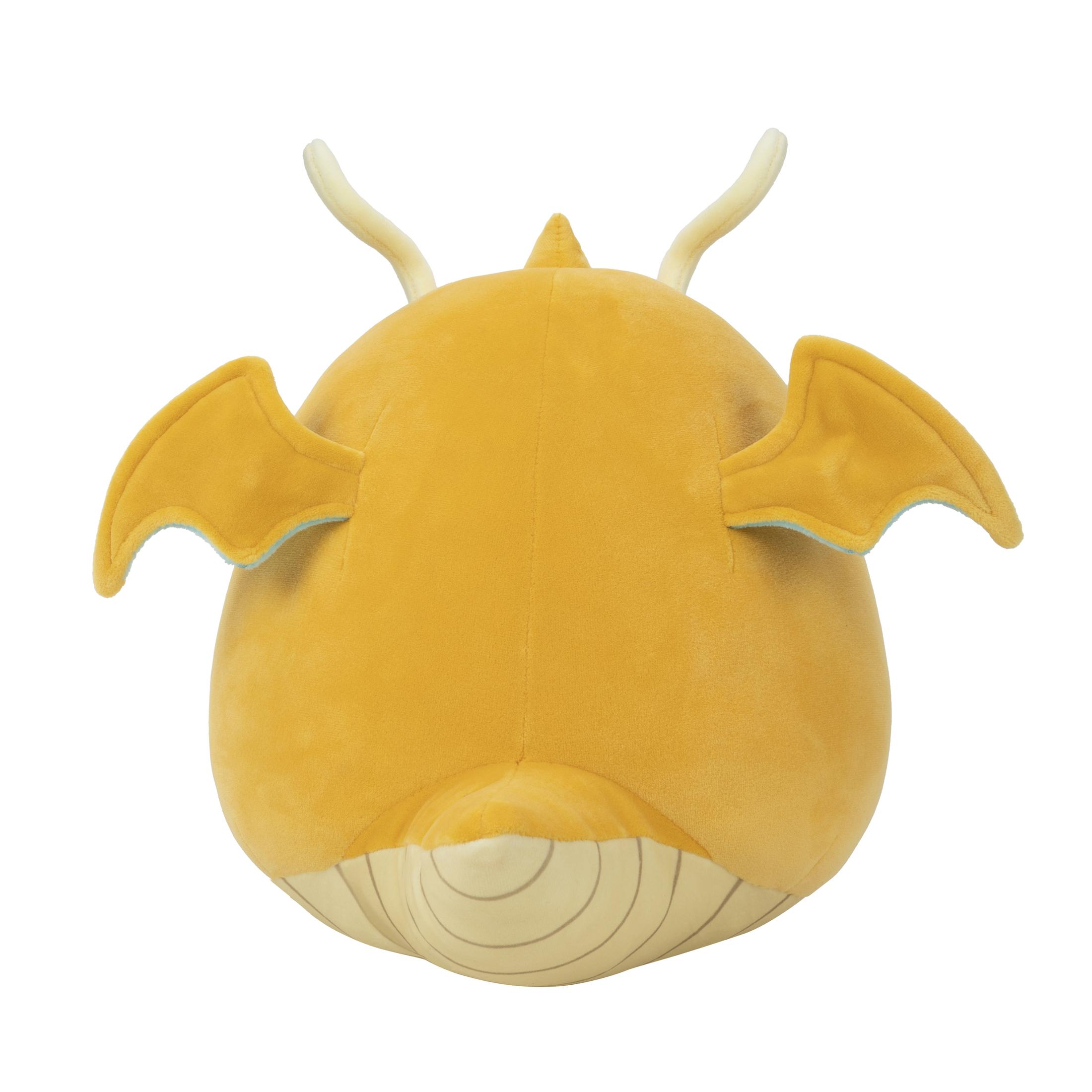 Un jouet dragon en peluche jaune, vu de dos, avec des ailes et des cornes.