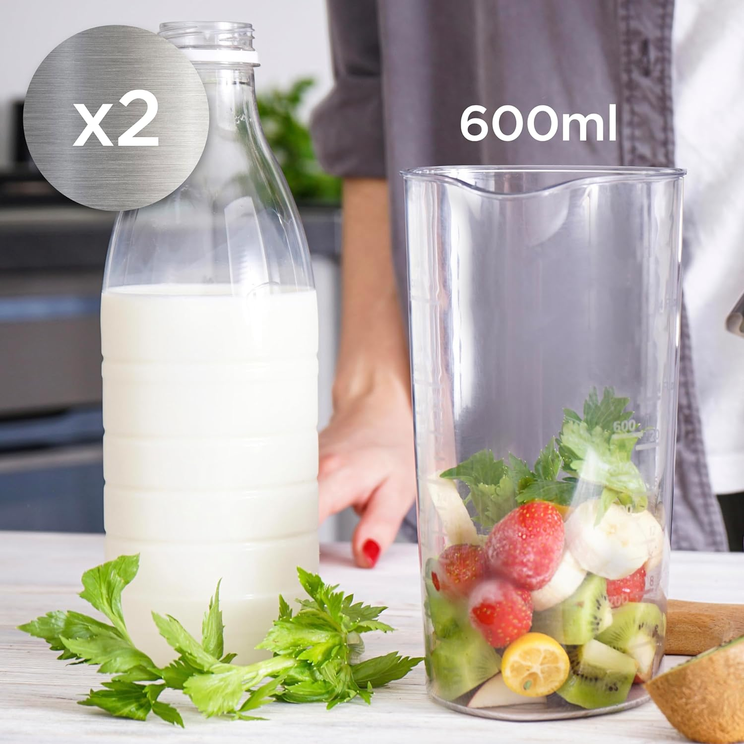 Eine Milchflasche und ein Mixer mit Zutaten. Der Mixer enthält Früchte und Grünzeug.