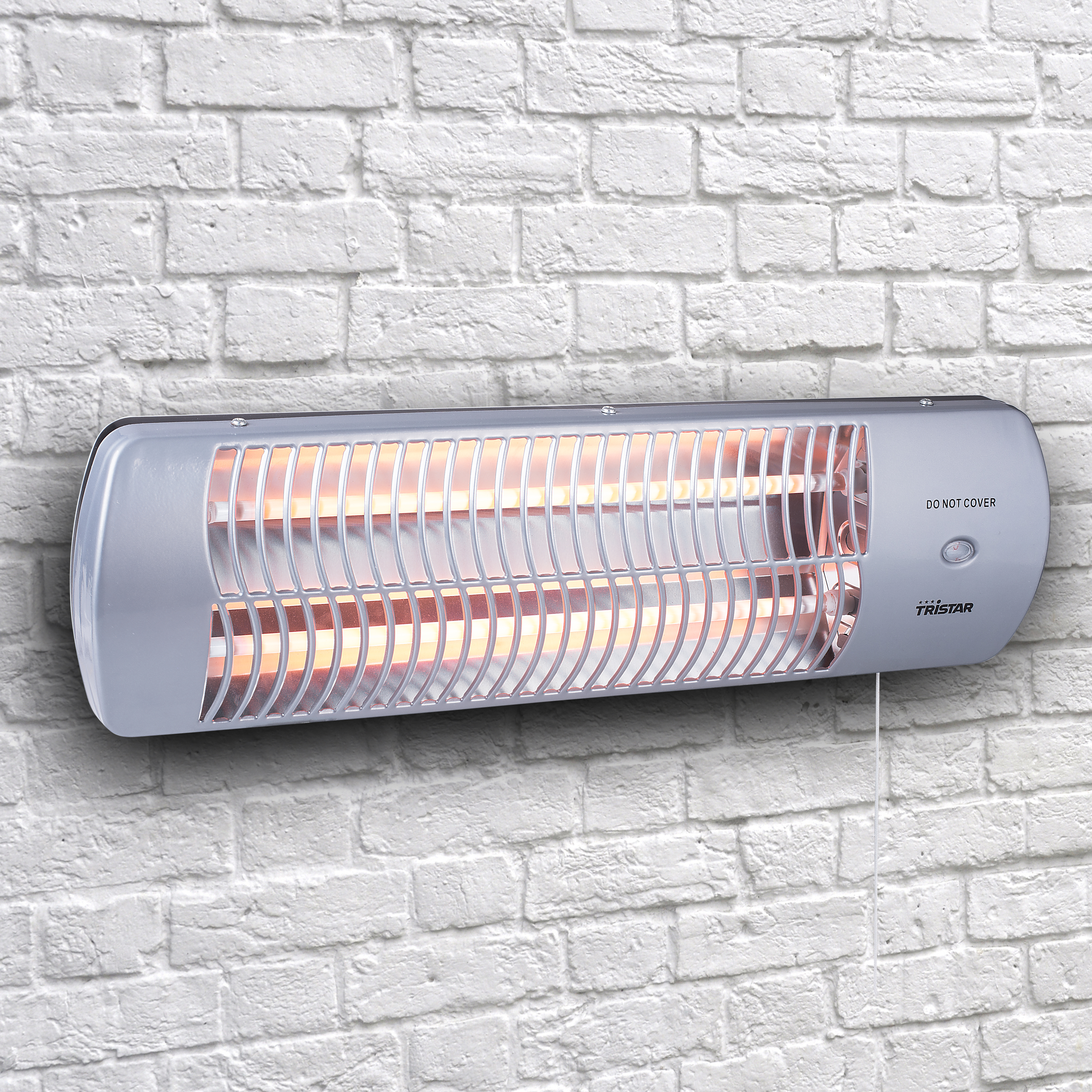 Een witte elektrische kachel gemonteerd op een bakstenen muur, met de woorden "NIET BEDEKKEN" erop.