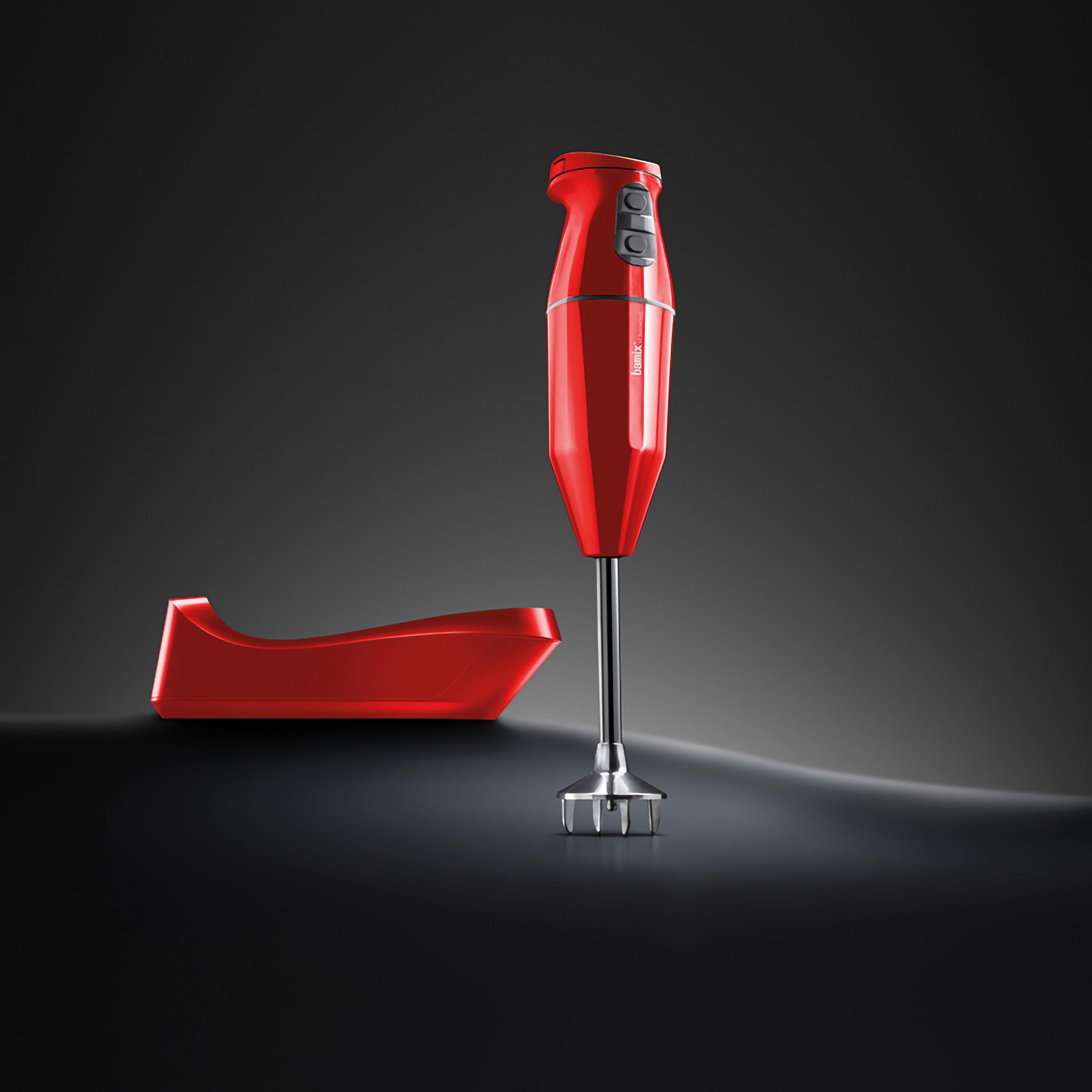 Frullatore a immersione rosso con base. Posto su sfondo scuro.