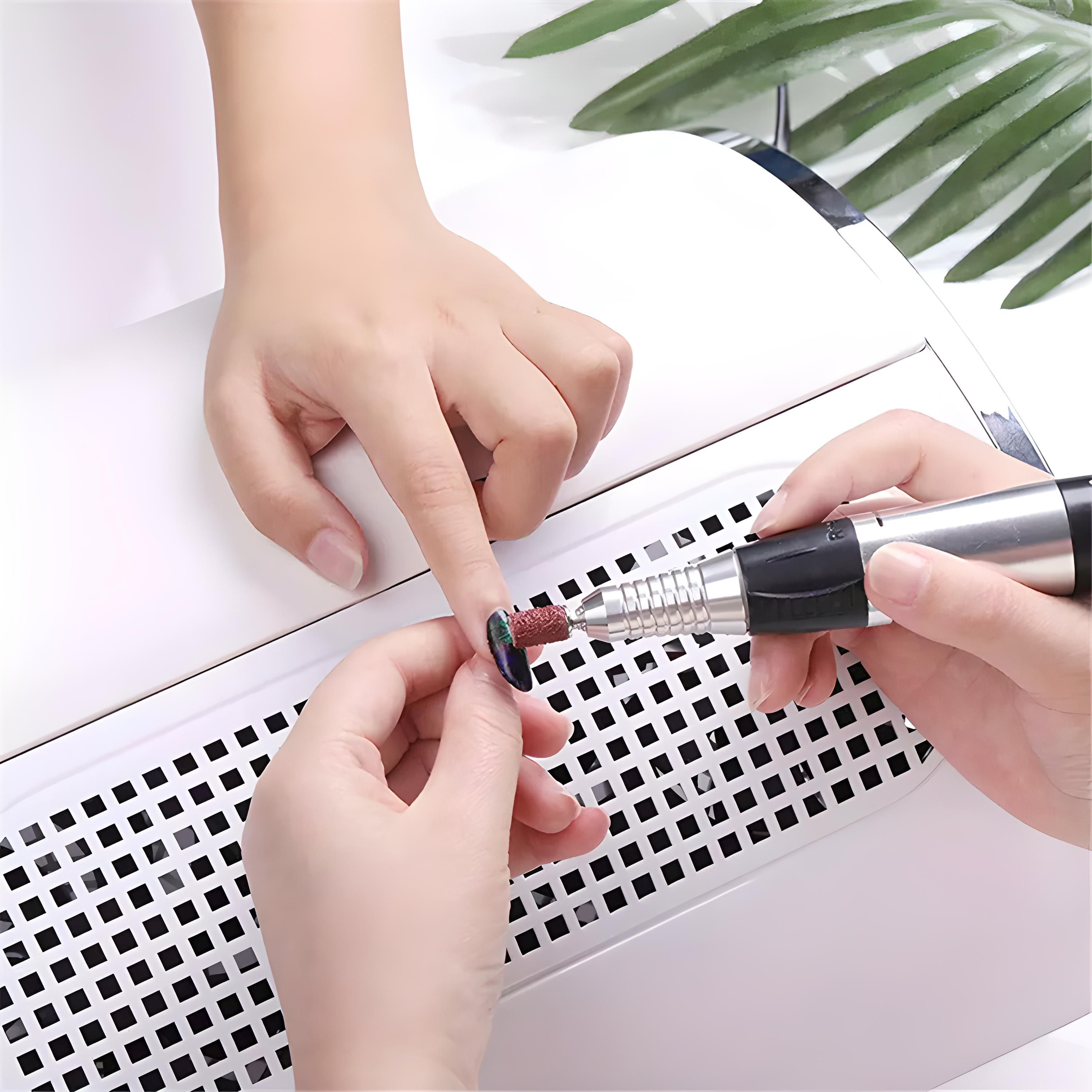 Eine Maniküristin benutzt einen Nagelbohrer an einem Fingernagel des Kunden.
