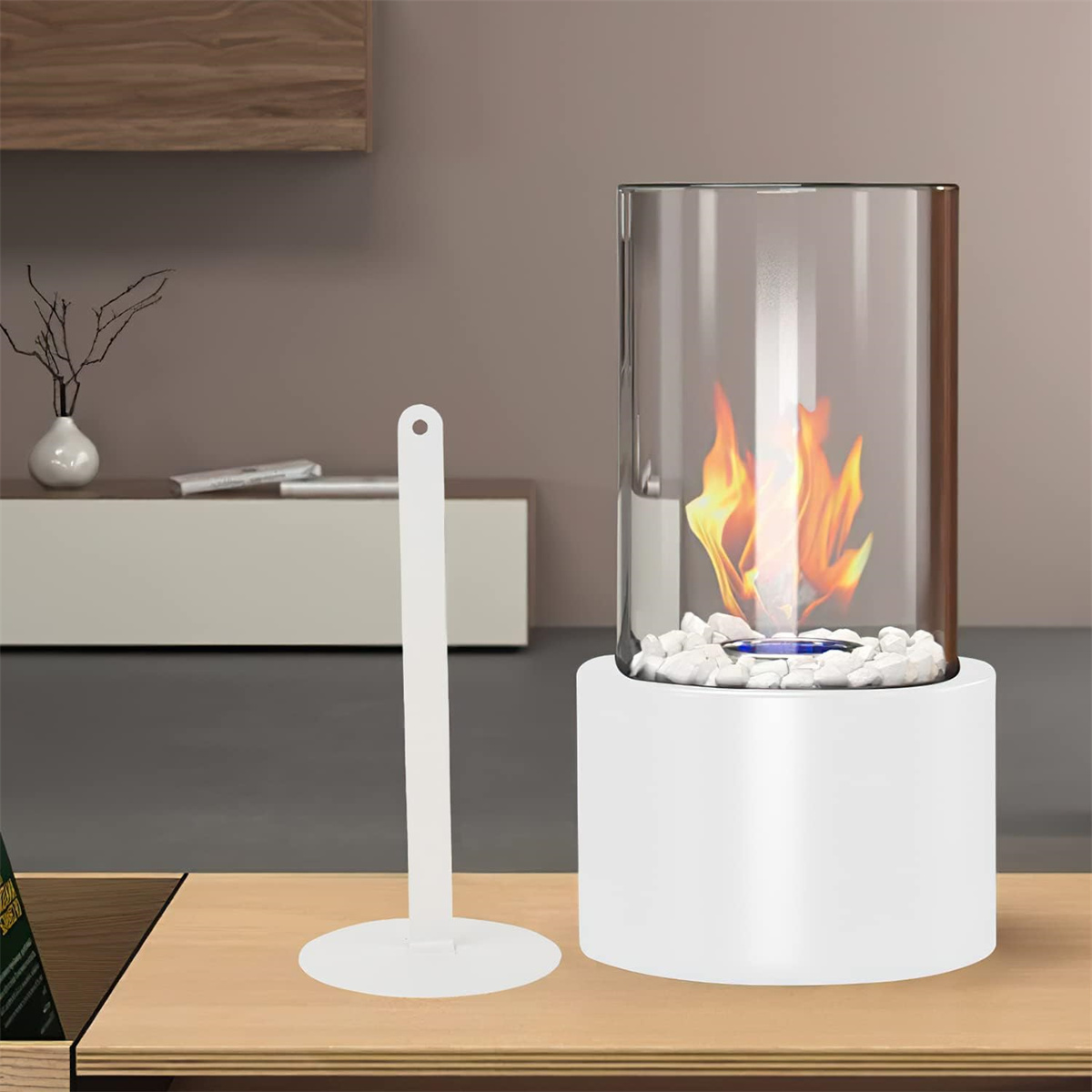 Weißer, zylindrischer Tischkamin mit Glas und weißen Steinen. Flammen sind sichtbar. Brauner Tisch.