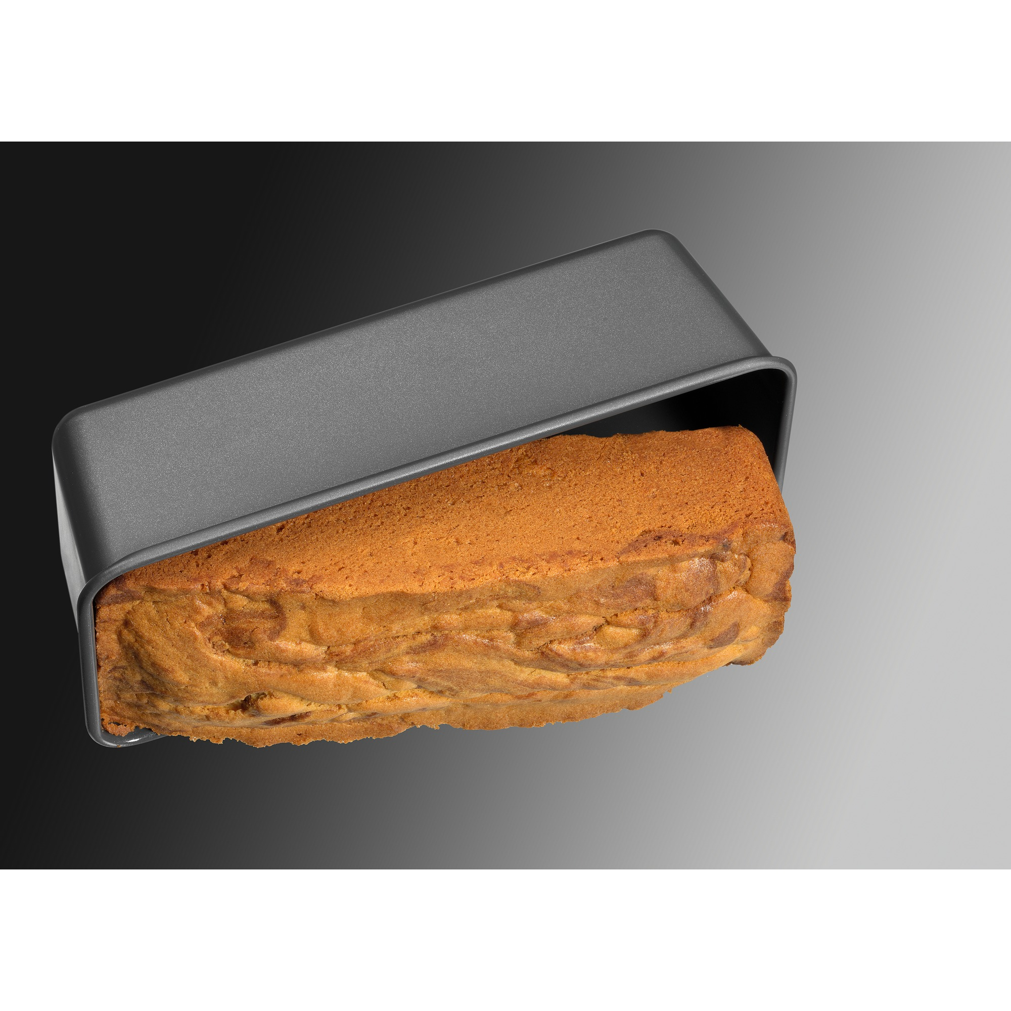 Eine graue Kastenform mit einem gebackenen Kuchen darin, vor einem Schwarz-Grau-Verlauf.