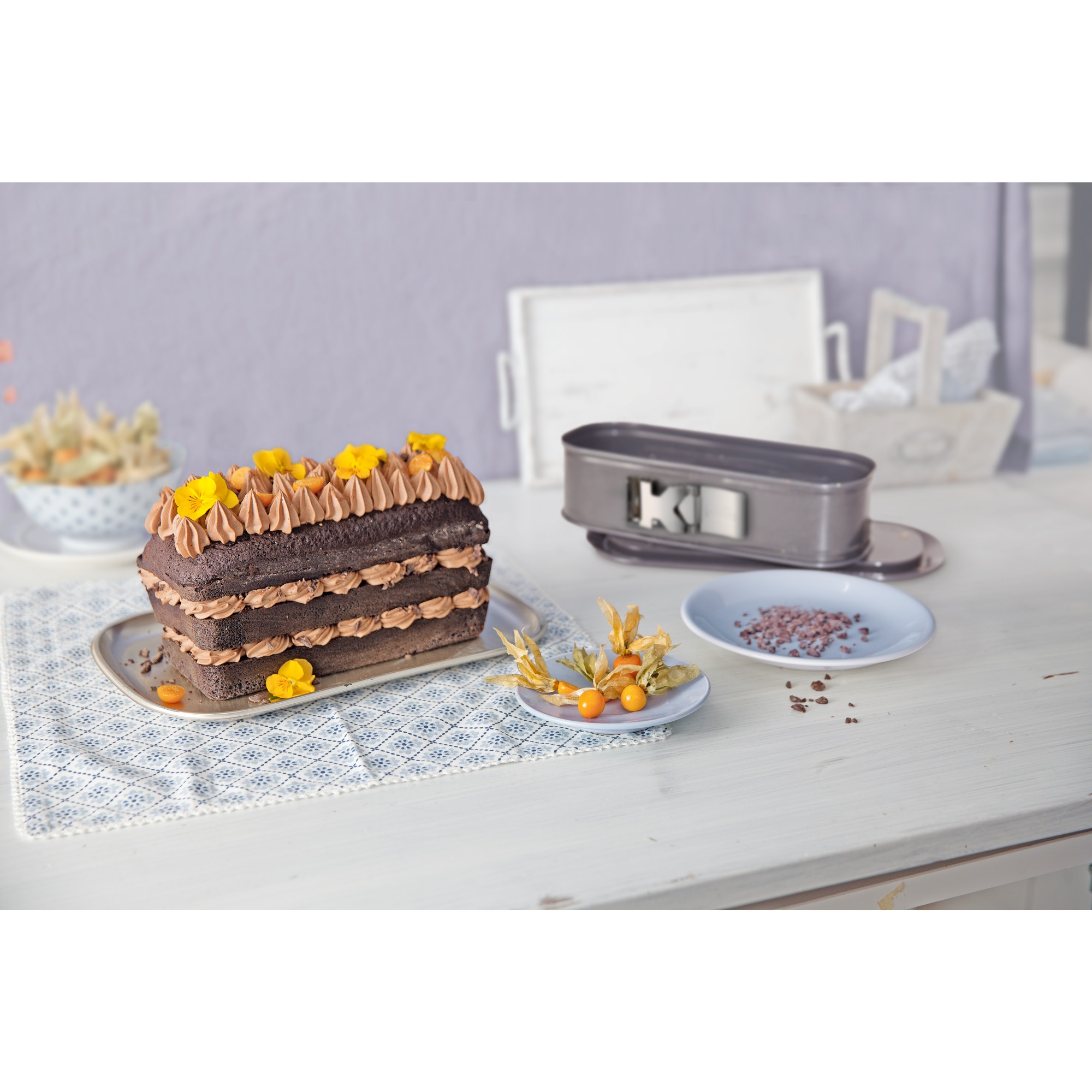 Warstwowe ciasto czekoladowe z lukrem i dekoracjami, z formami do ciasta.