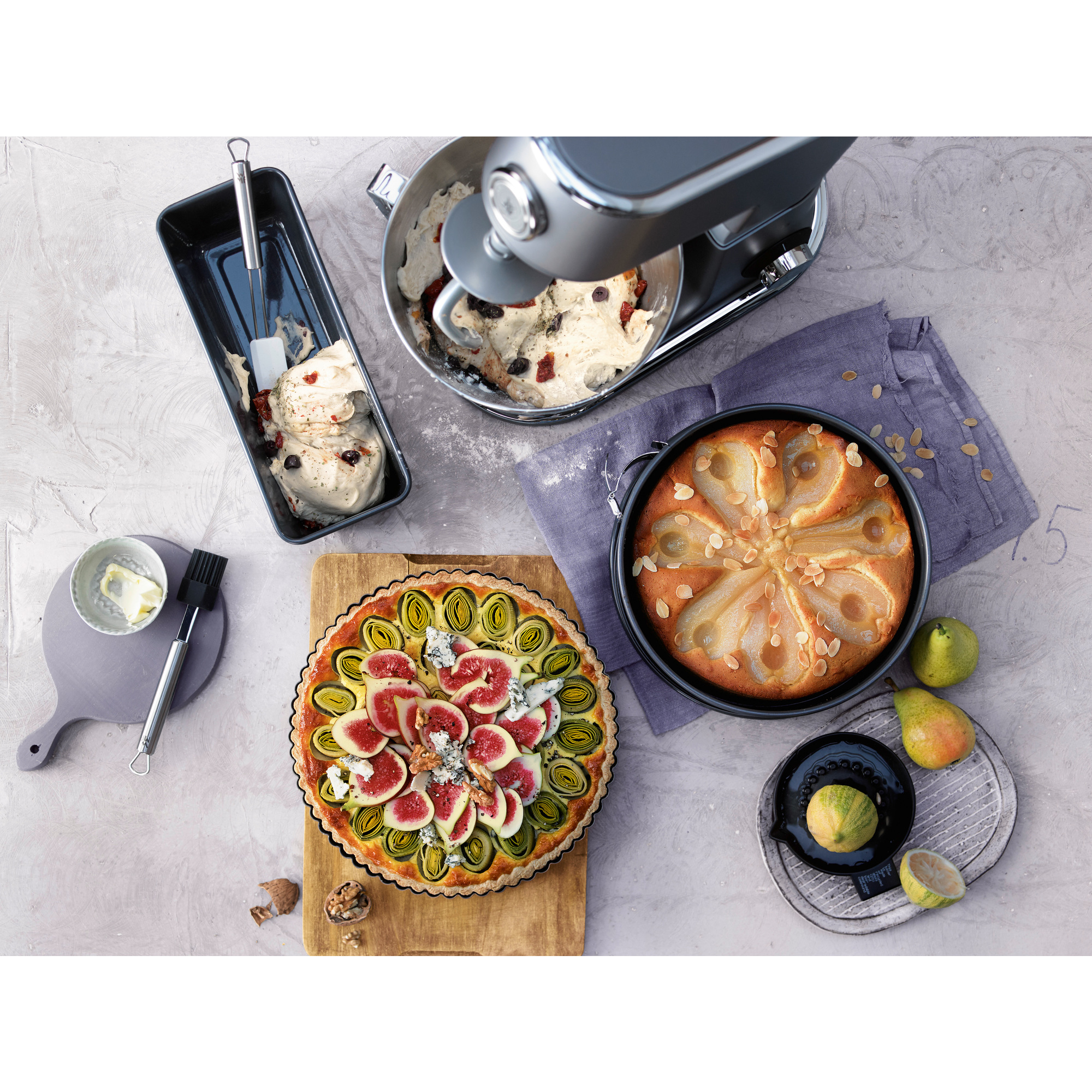 Widok z góry na stół z mikserem, tartą, ciastem i innymi narzędziami do pieczenia. Różne składniki.