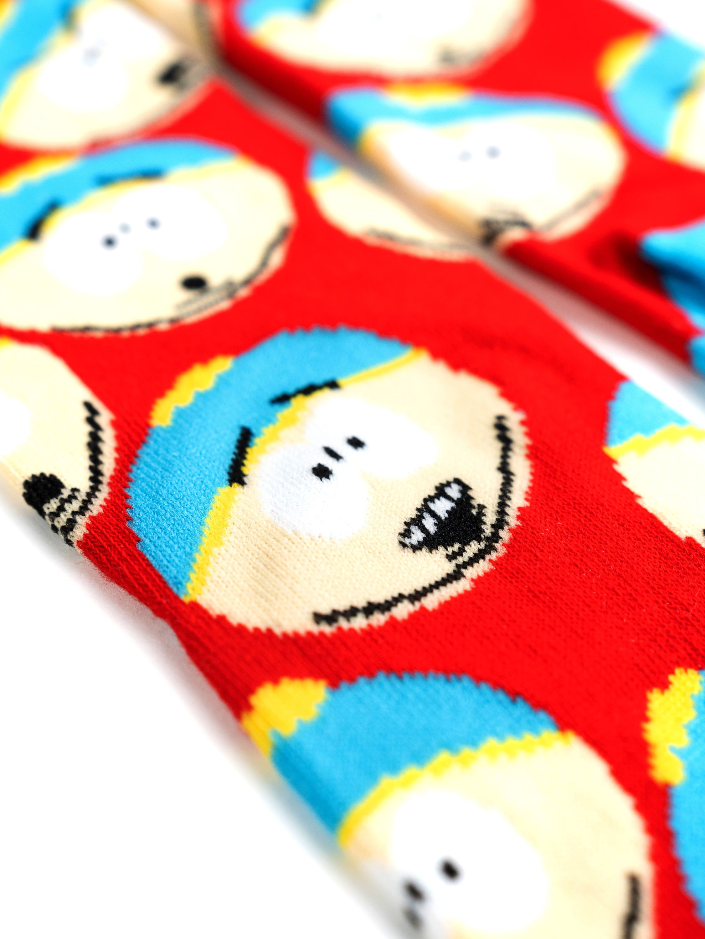 South Park Socken mit Cartmans Gesicht. Rote Socken mit blauen und gelben Details. Weißer Hintergrund.