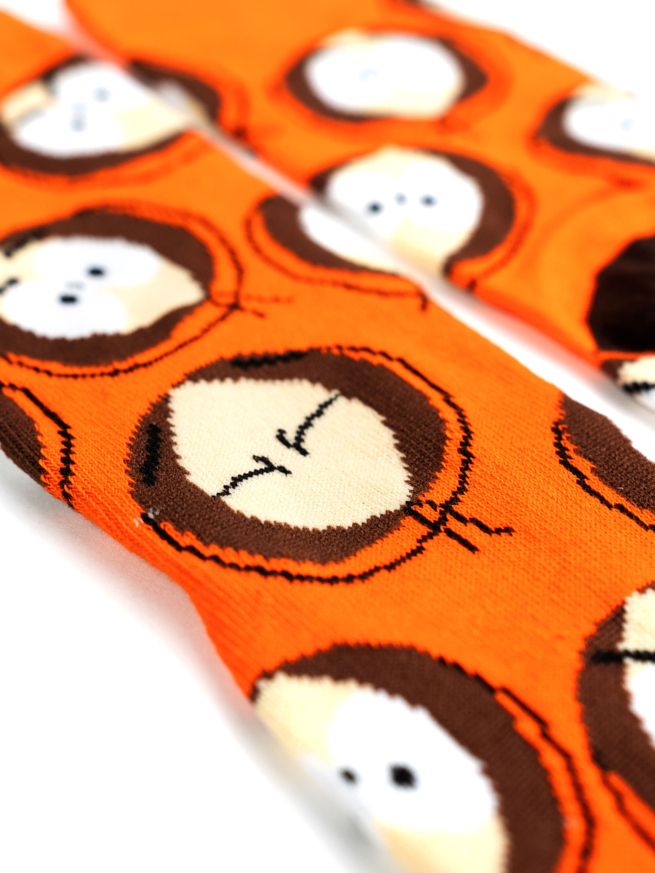 Orangefarbene Socken mit einem Muster aus Cartoon-Gesichtern mit braunen Haaren und weißen Augen.