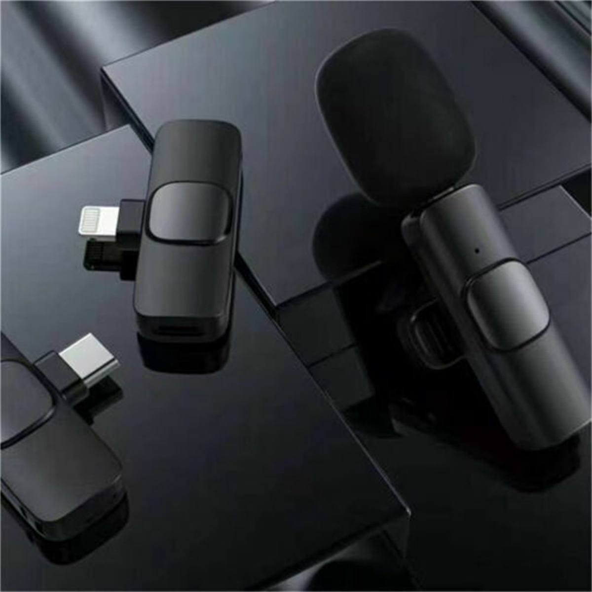 Schwarzes, kabelloses Mikrofon-Set mit Lightning- und USB-C-Adapter. Reflektierende schwarze Oberfläche.