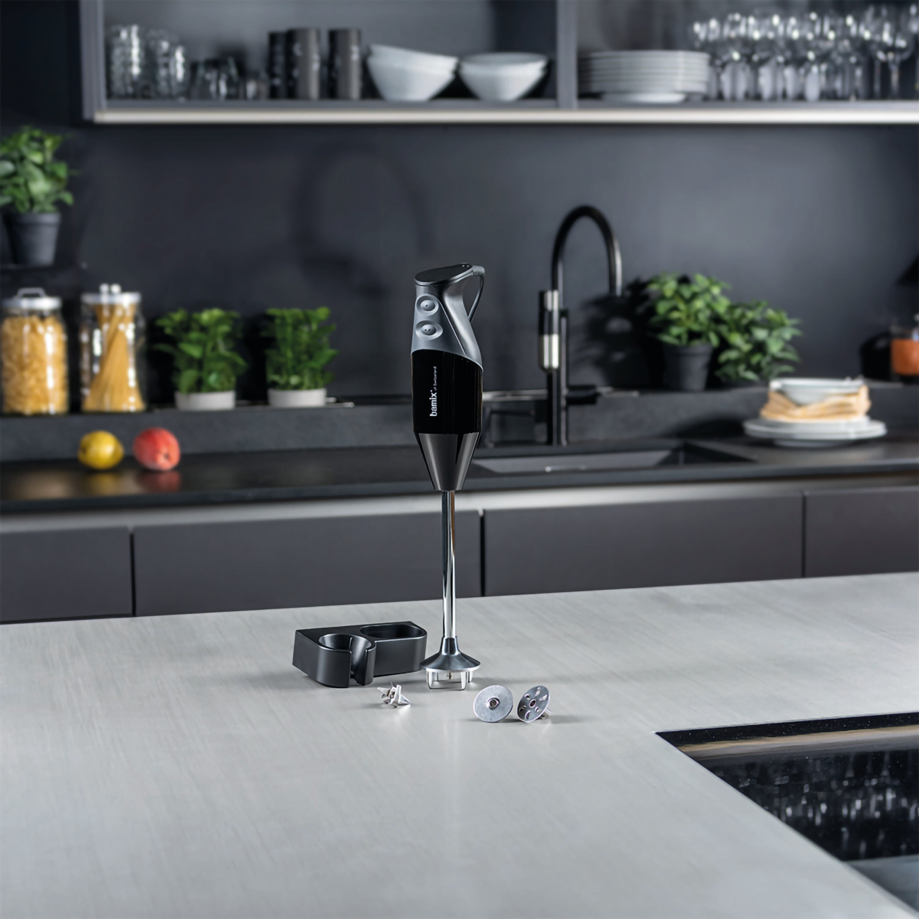 Frullatore a immersione nero con accessori su un piano cucina.