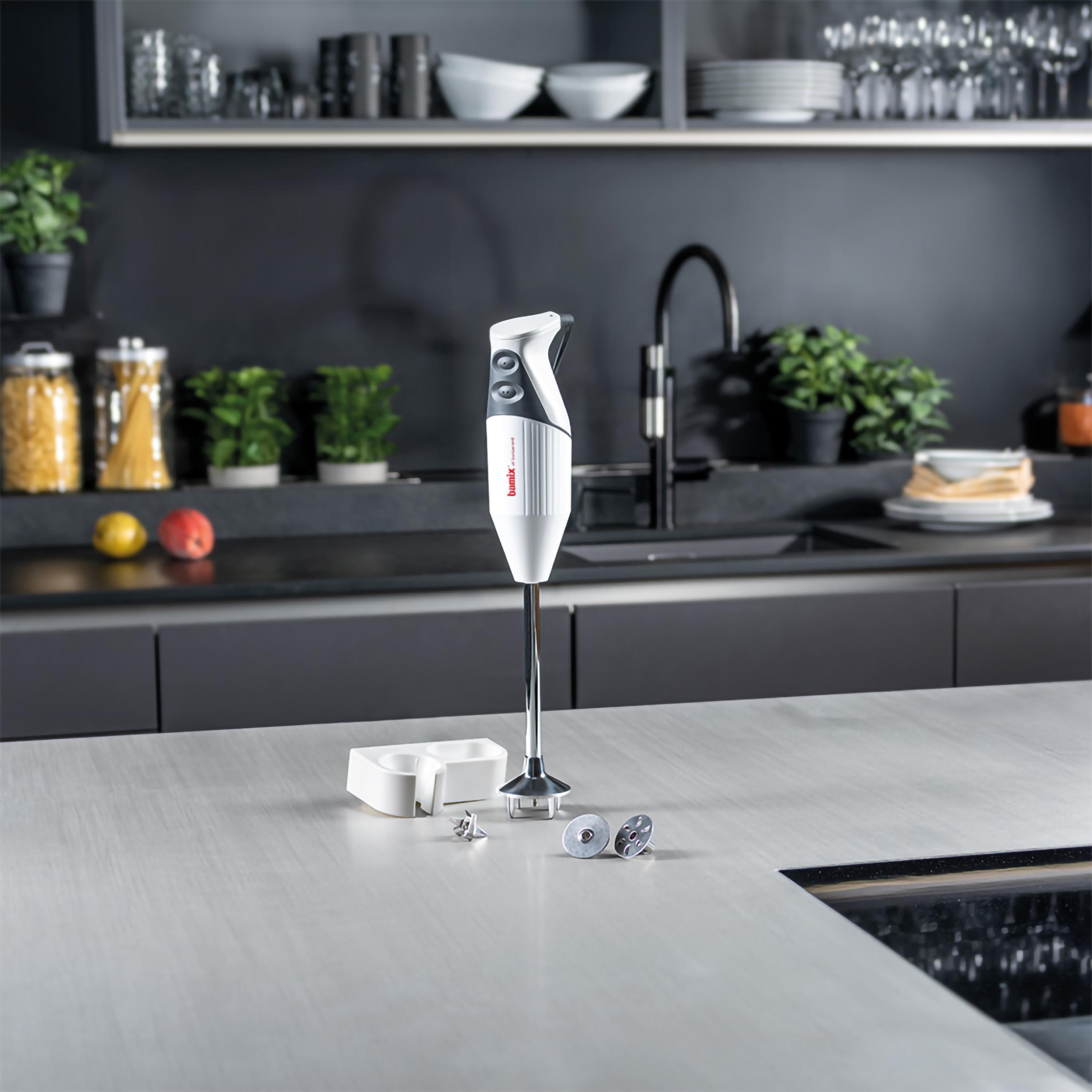 Frullatore a immersione bianco con accessori su un piano cucina.