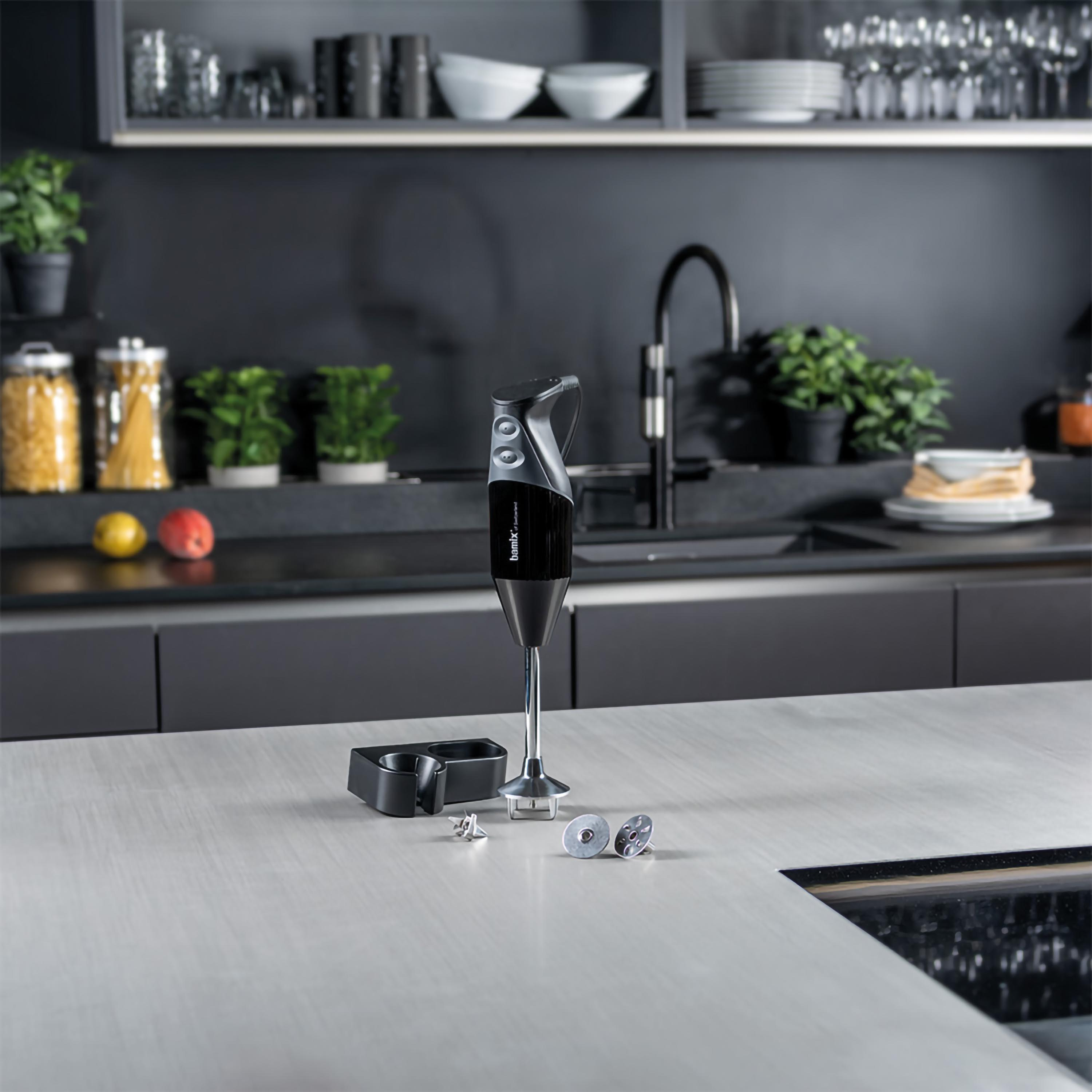 Un frullatore a immersione con accessori su un piano cucina.